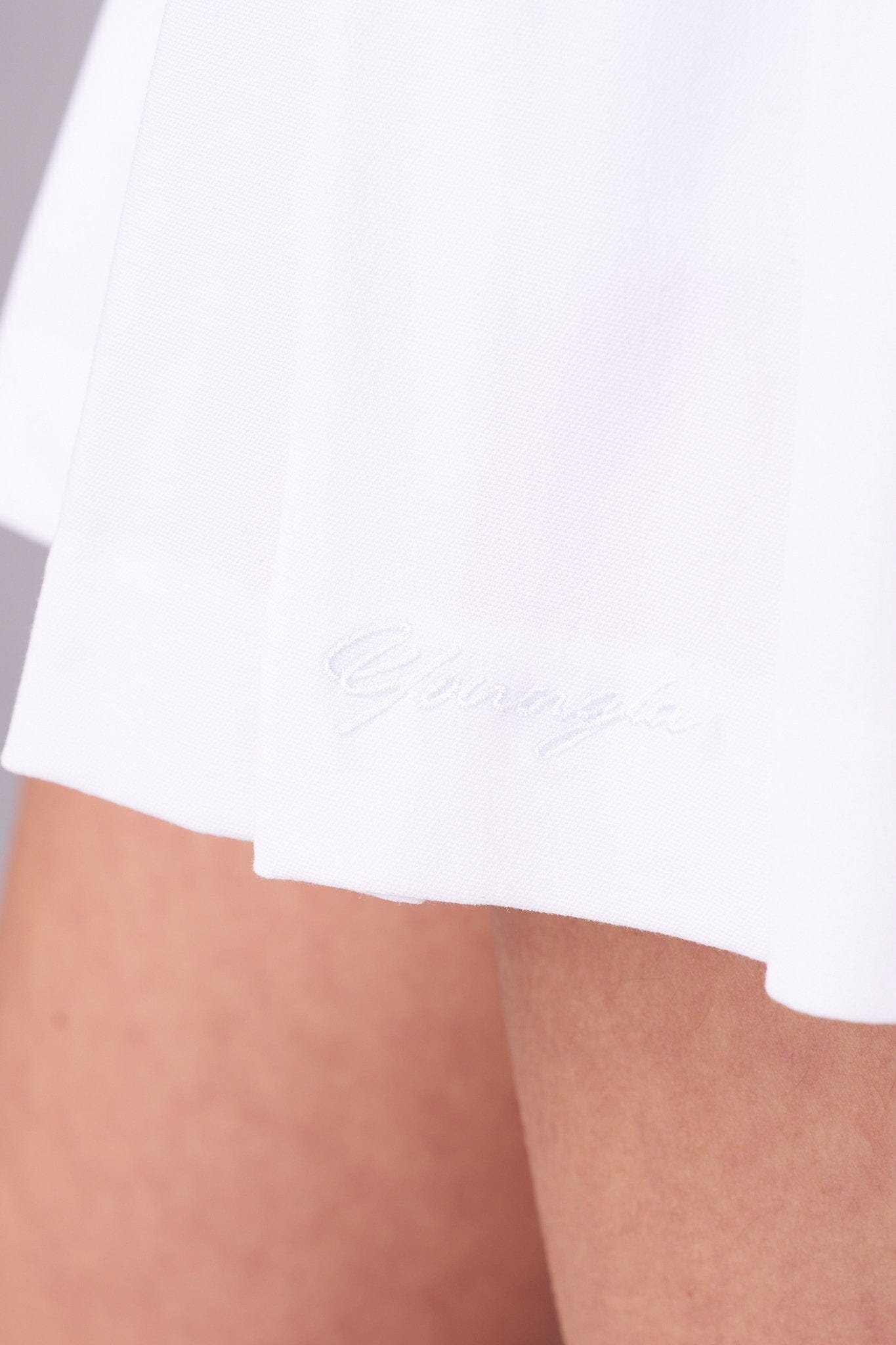 Lifestyle shot of model walking outdoors in white mini skirt with compression shorts