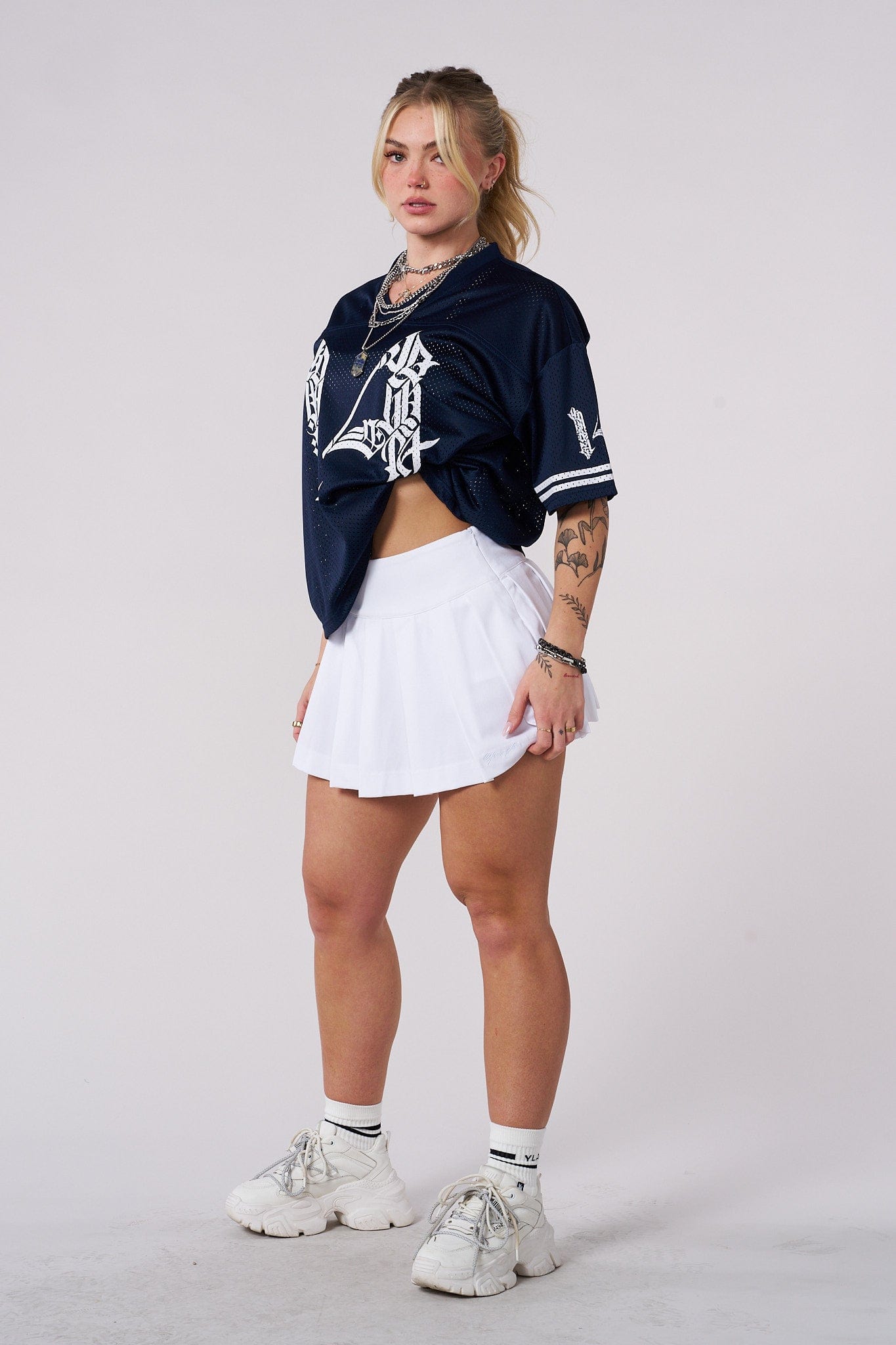 Lifestyle shot of model walking outdoors in white mini skirt with compression shorts