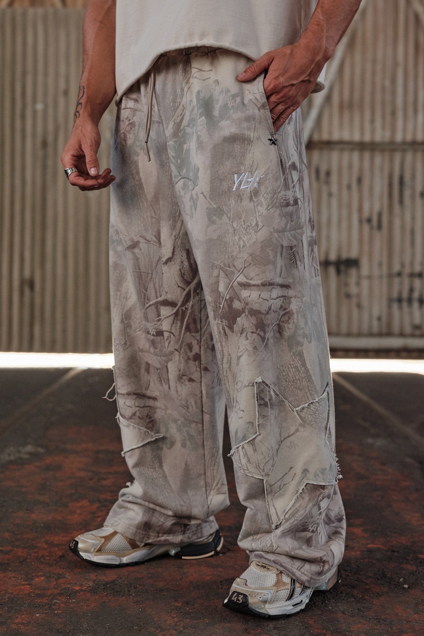 Side view of the baggy gray sweatpants with star patches.