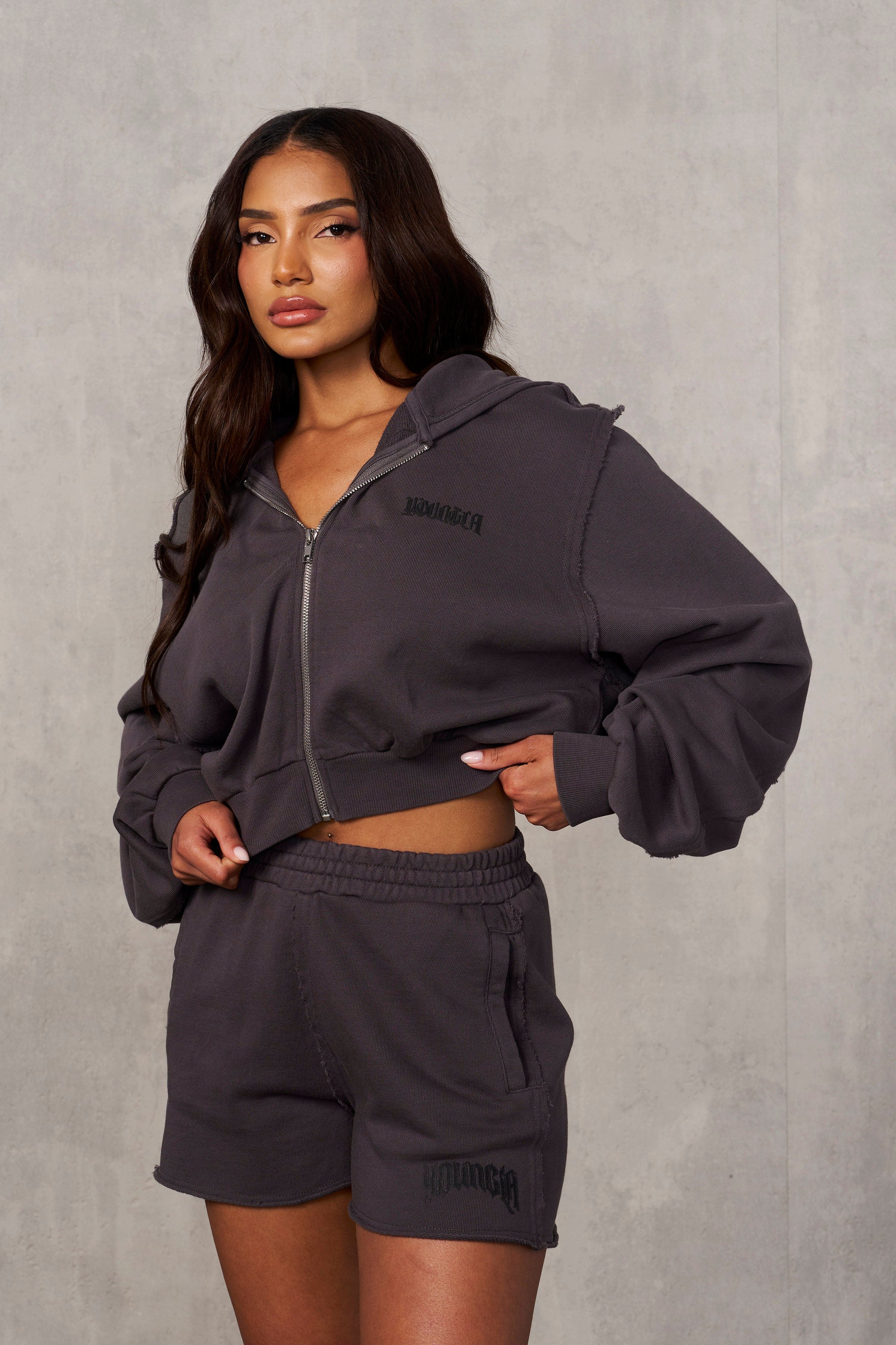 Close-up of raw-edge stitching and logo on cropped zip up hoodie