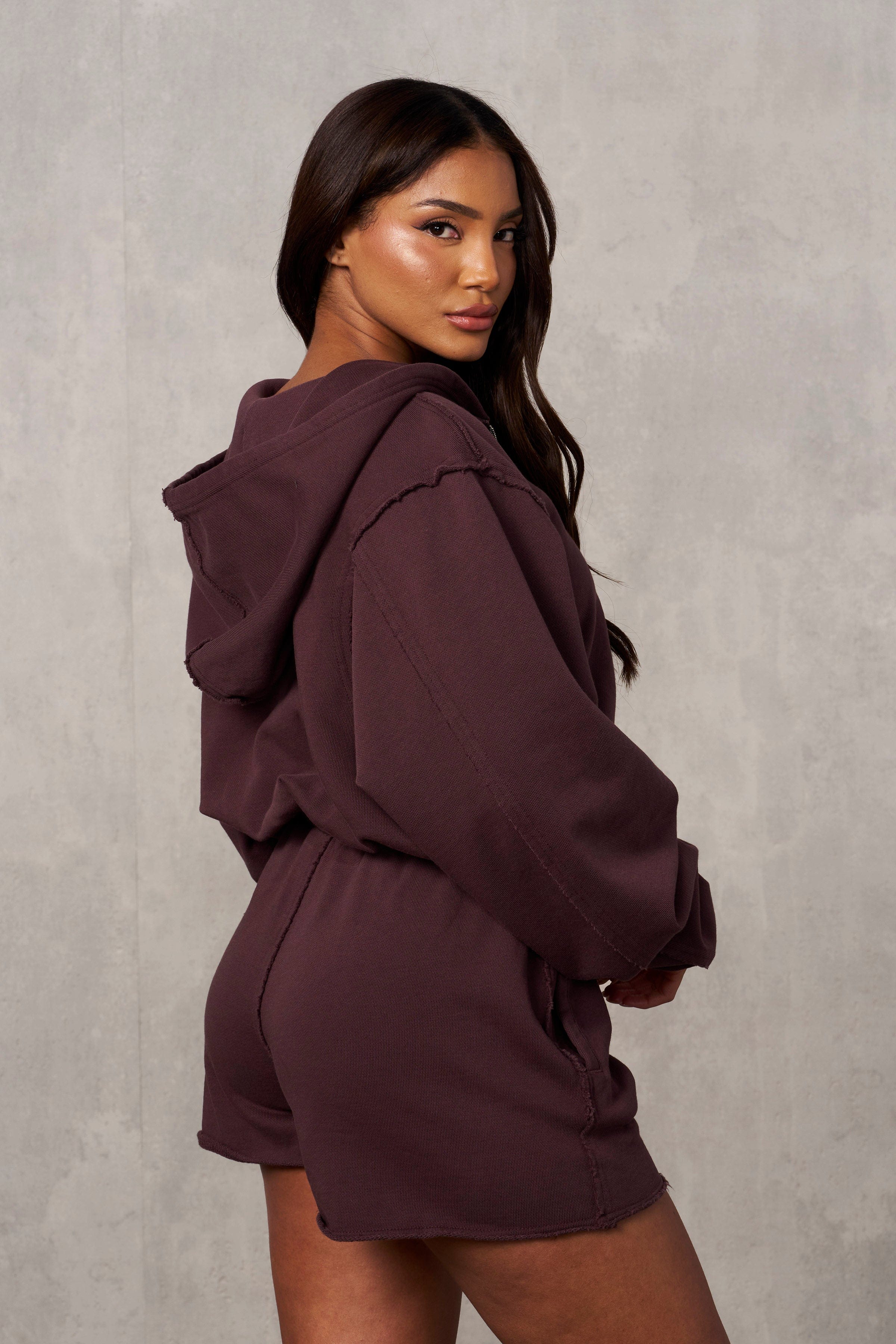 Close-up of raw-edge stitching and logo on cropped zip up hoodie