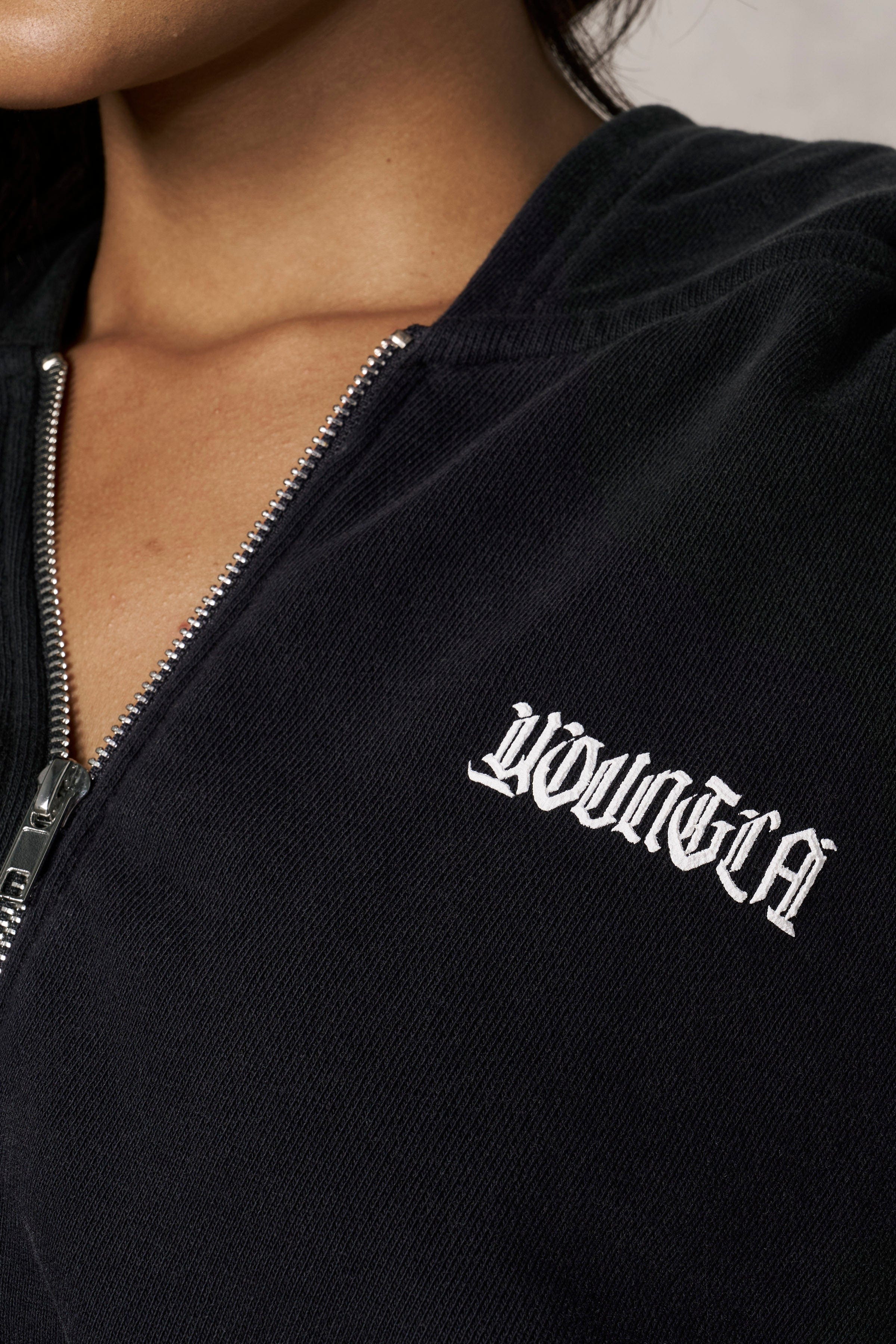 Close-up of raw-edge stitching and logo on cropped zip up hoodie