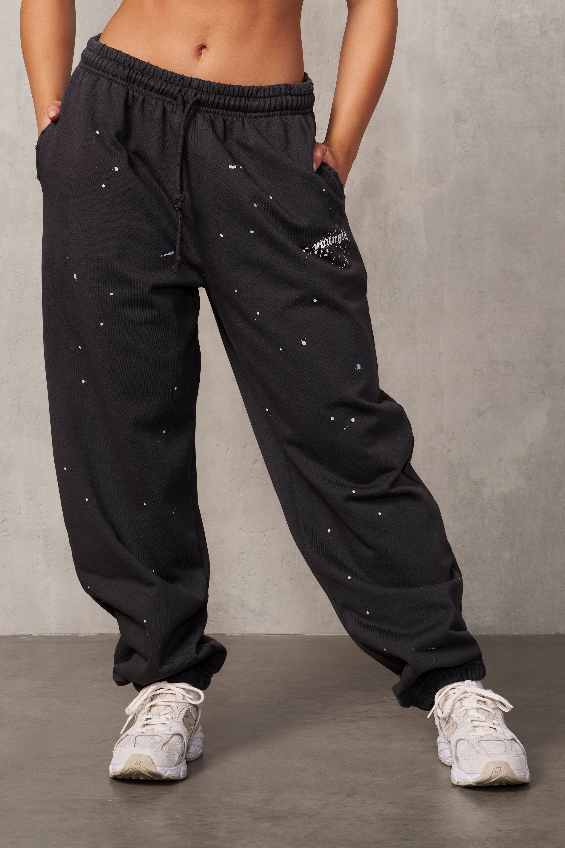 Side profile of the model wearing black oversized sweat pants with urban backdrop.