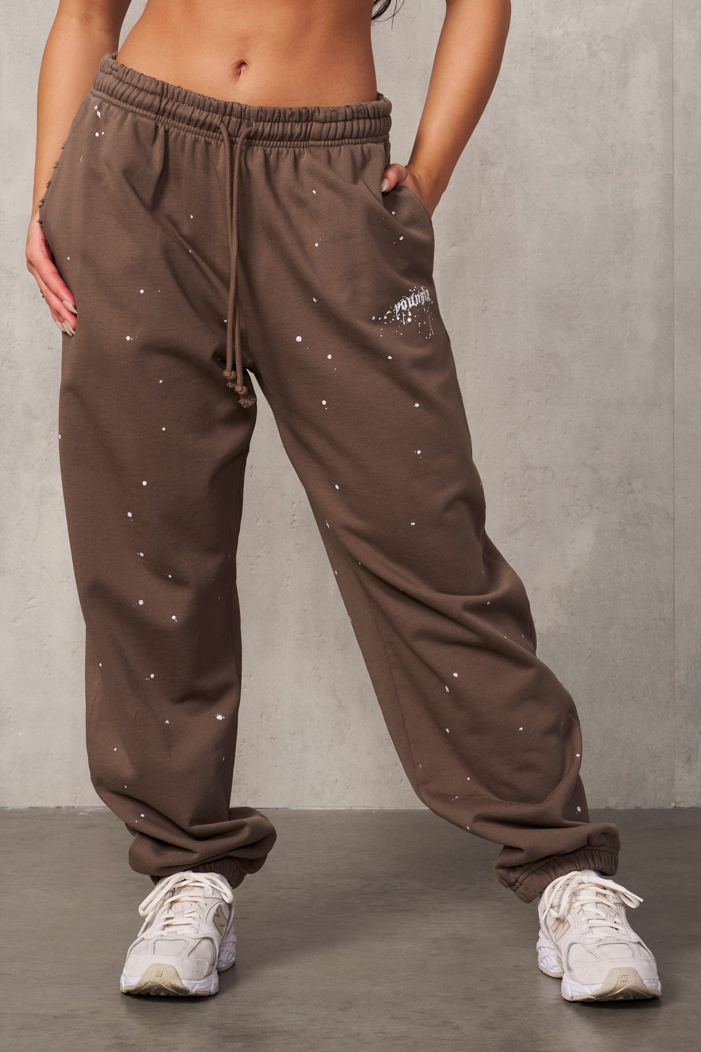 Side profile of the model wearing black oversized sweat pants with urban backdrop.
