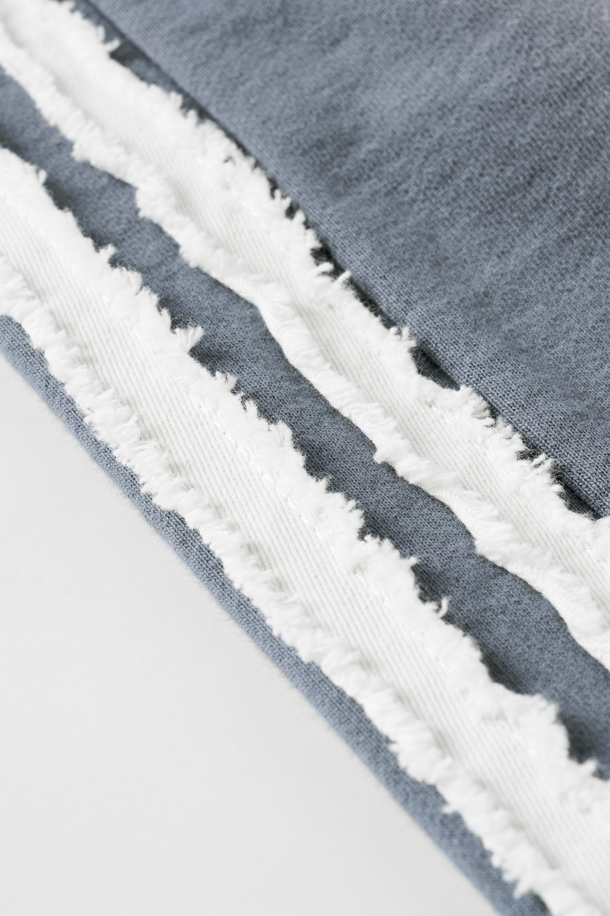 Side view of cotton sweat shorts, highlighting the raw-cut stripes.