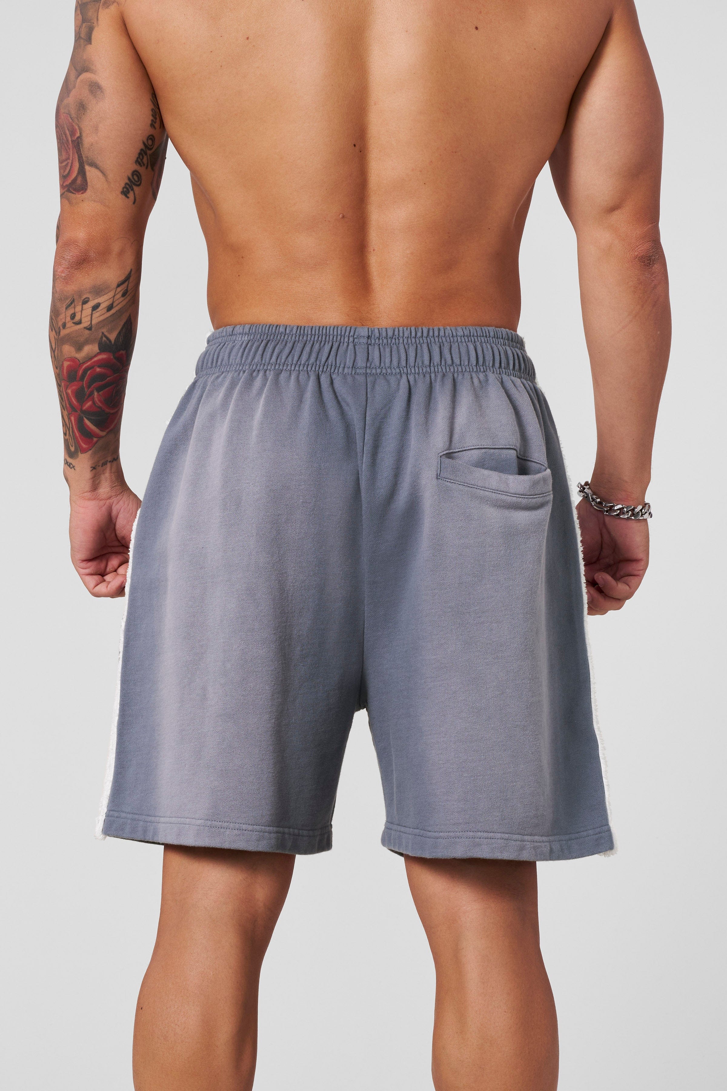 Side view of cotton sweat shorts, highlighting the raw-cut stripes.