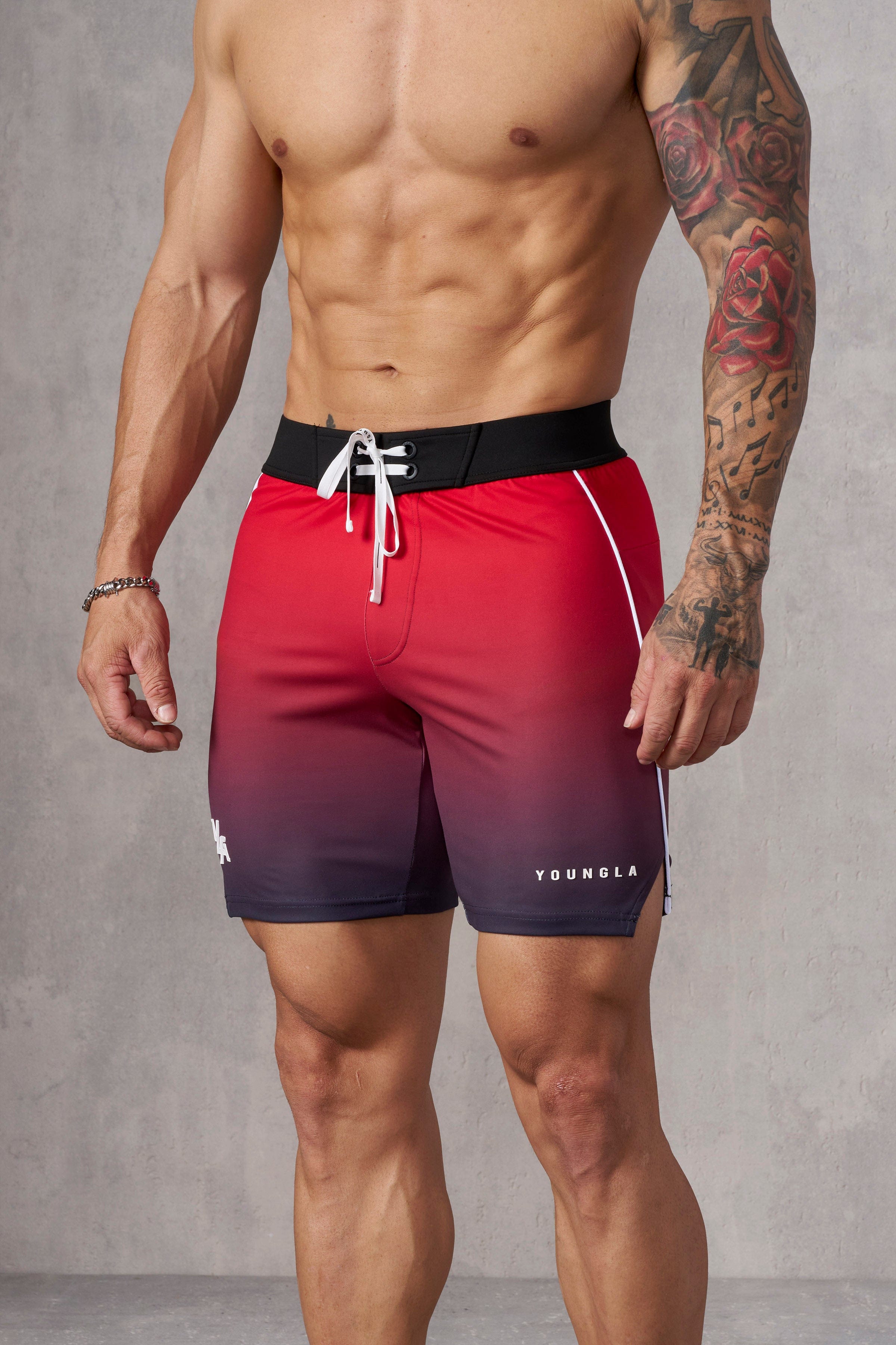 Model wearing mens physique board shorts during a competition.