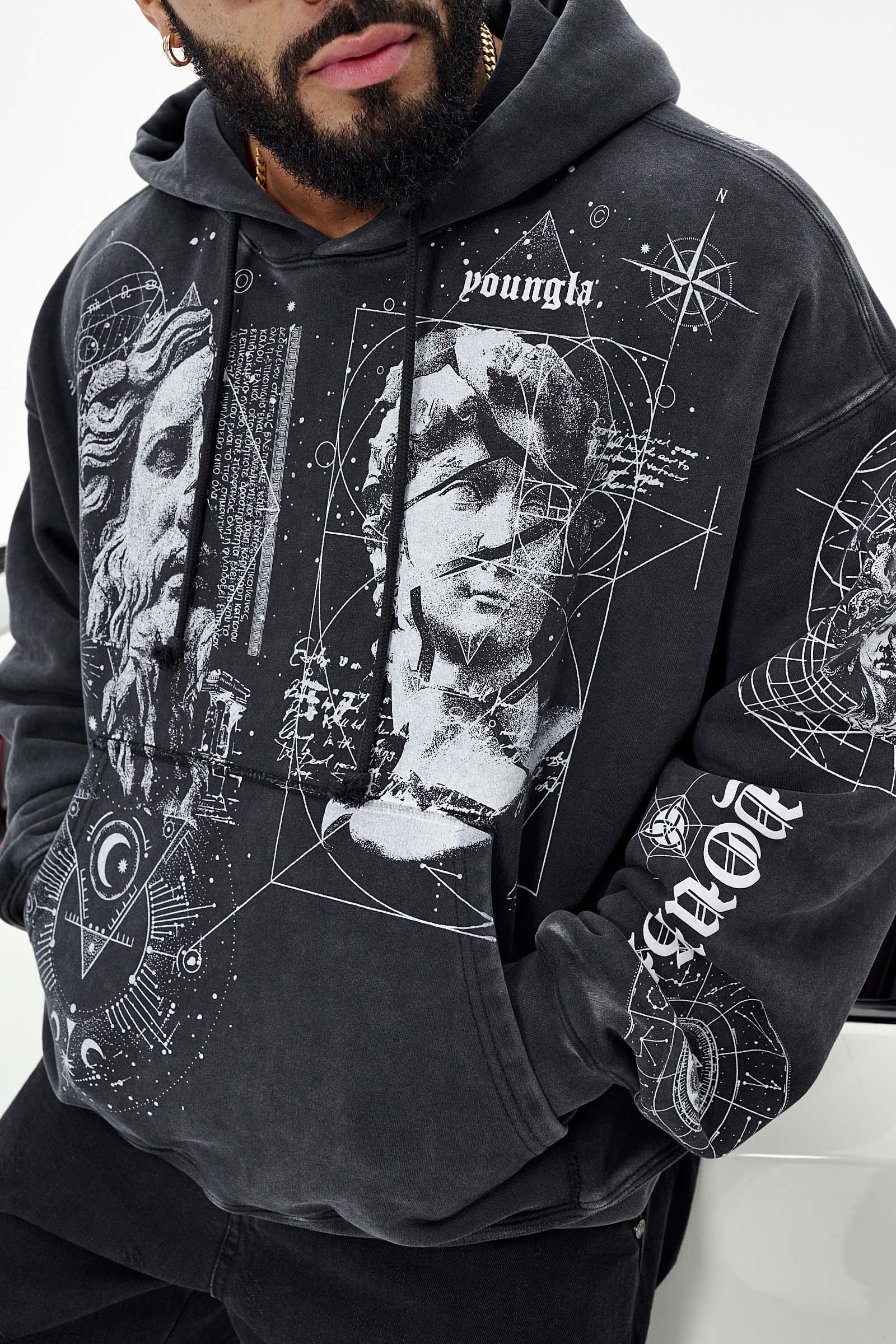 Model wearing a Renaissance hoodie showcasing artistic tattoo designs in an urban setting