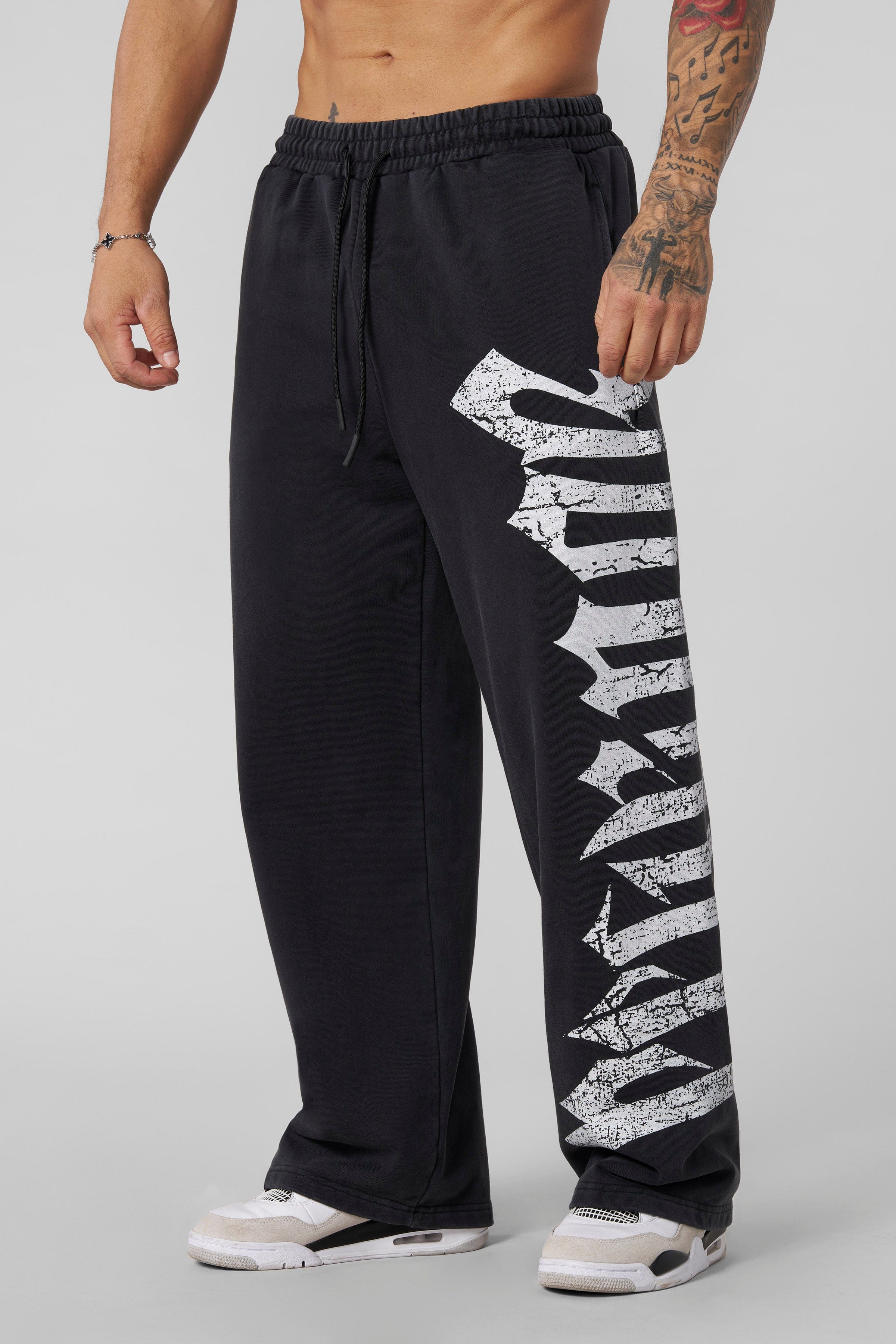 Full-body shot of model wearing black joggers styled with hoodie in urban setting
