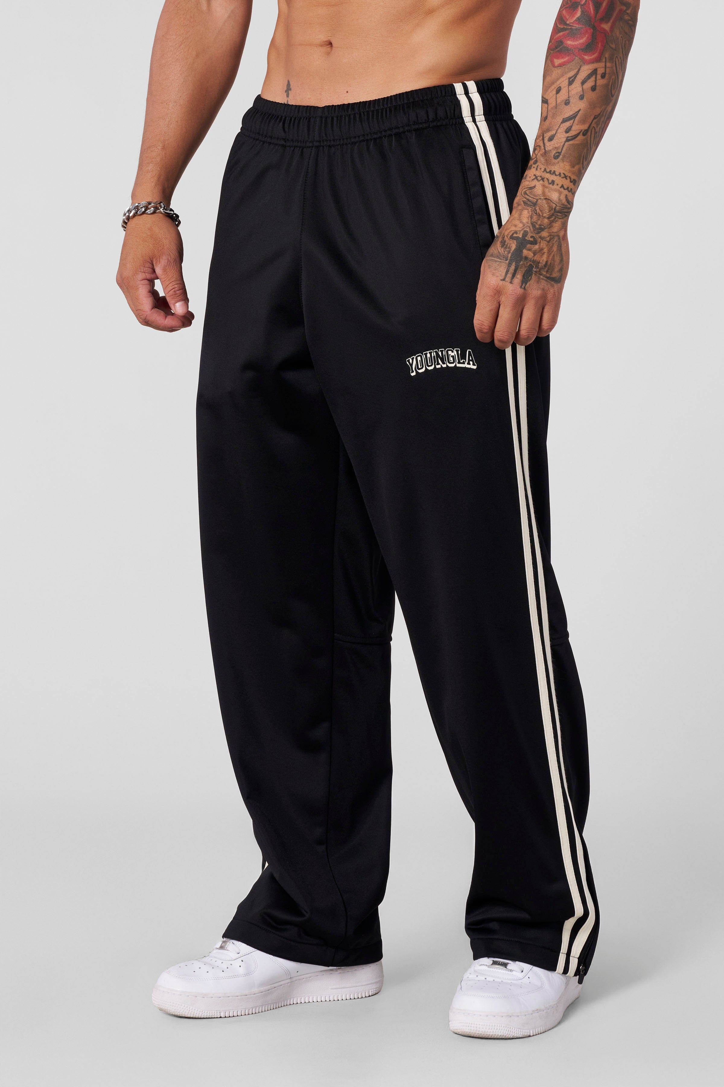 Front view of baggy track pants with stripe detail and zippered cuffs
