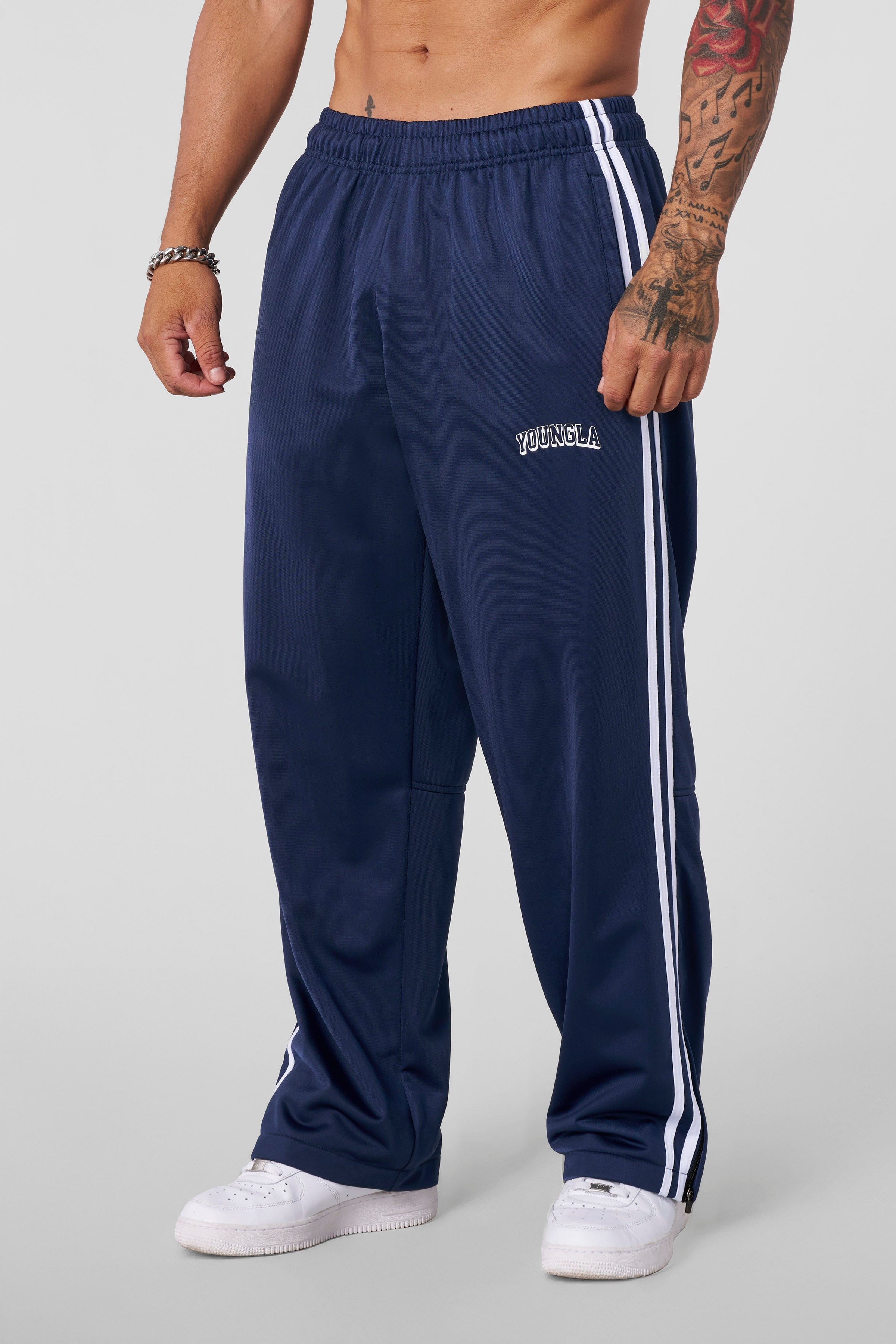 Front view of baggy track pants with stripe detail and zippered cuffs