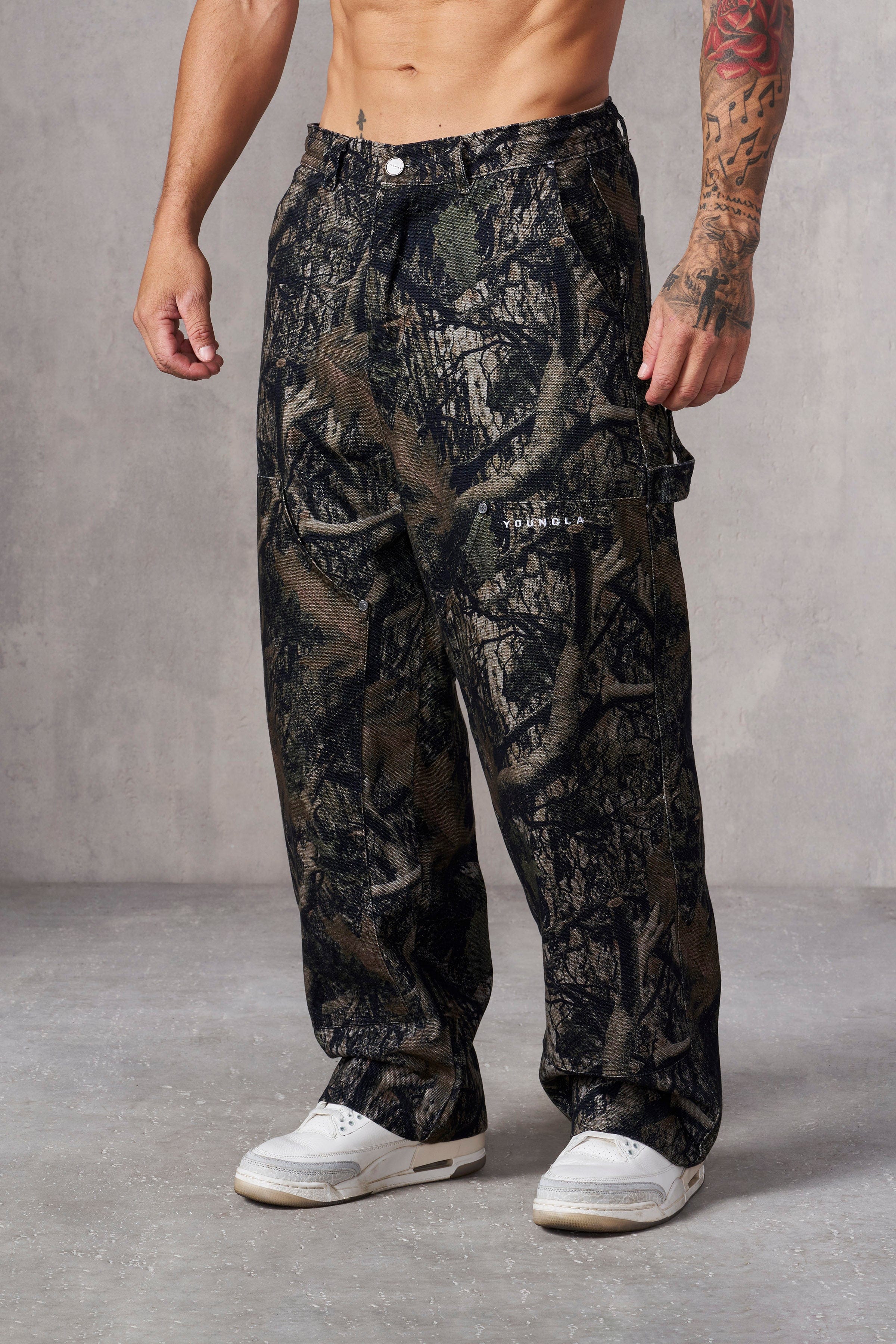 Model wearing tree camo carpenter jeans in a street-style pose.