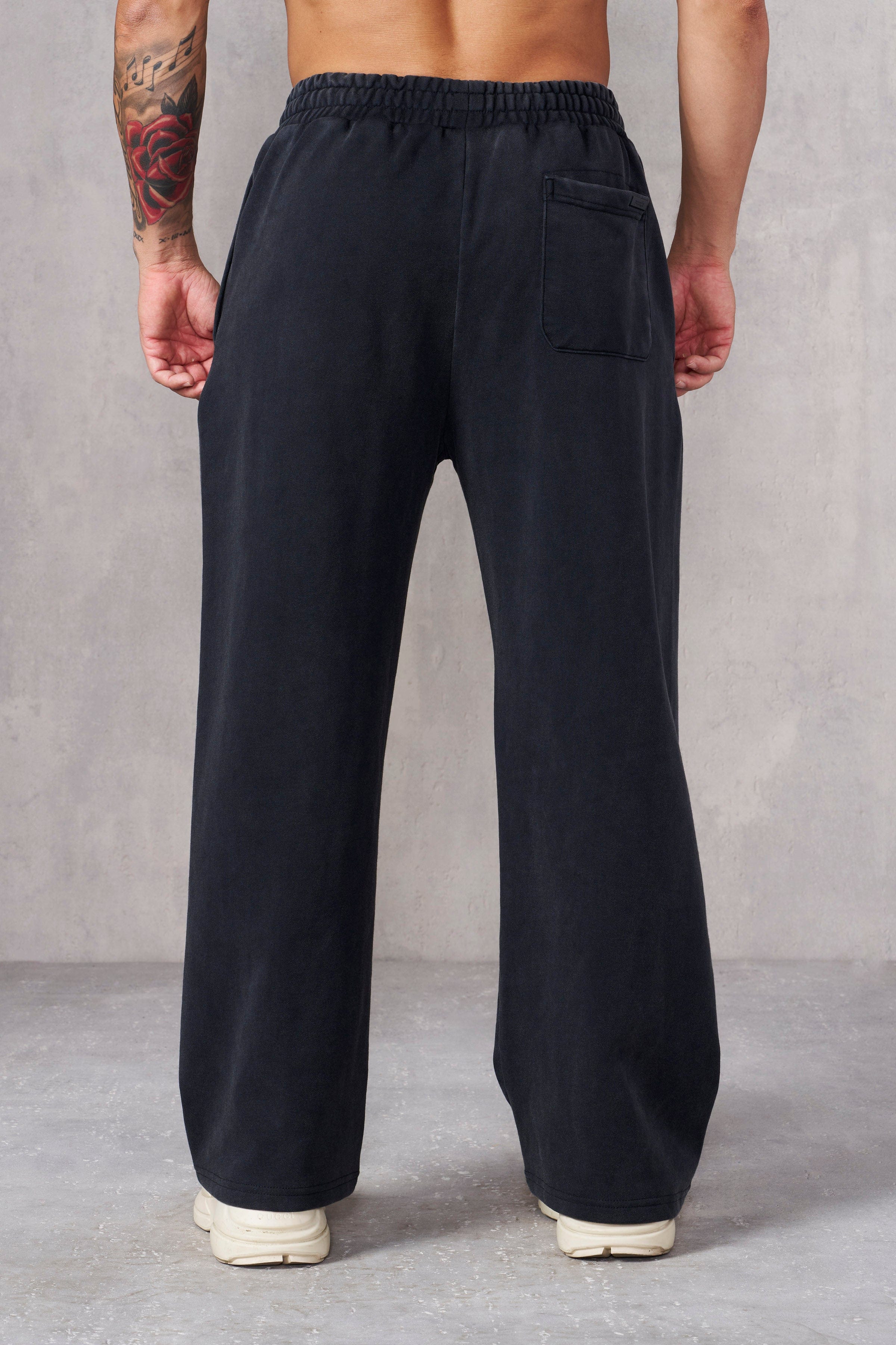 Front view of black baggy sweatpants on a model outdoors.