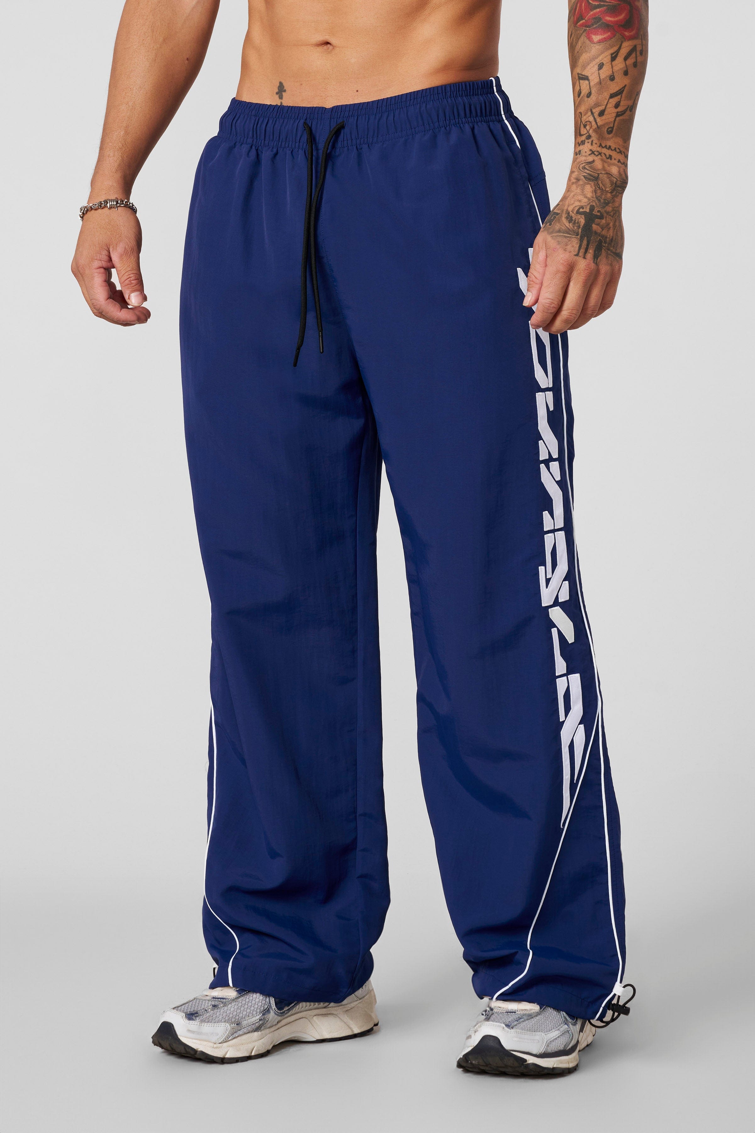 Side view of track pants highlighting the patch logo and lightweight fabric.