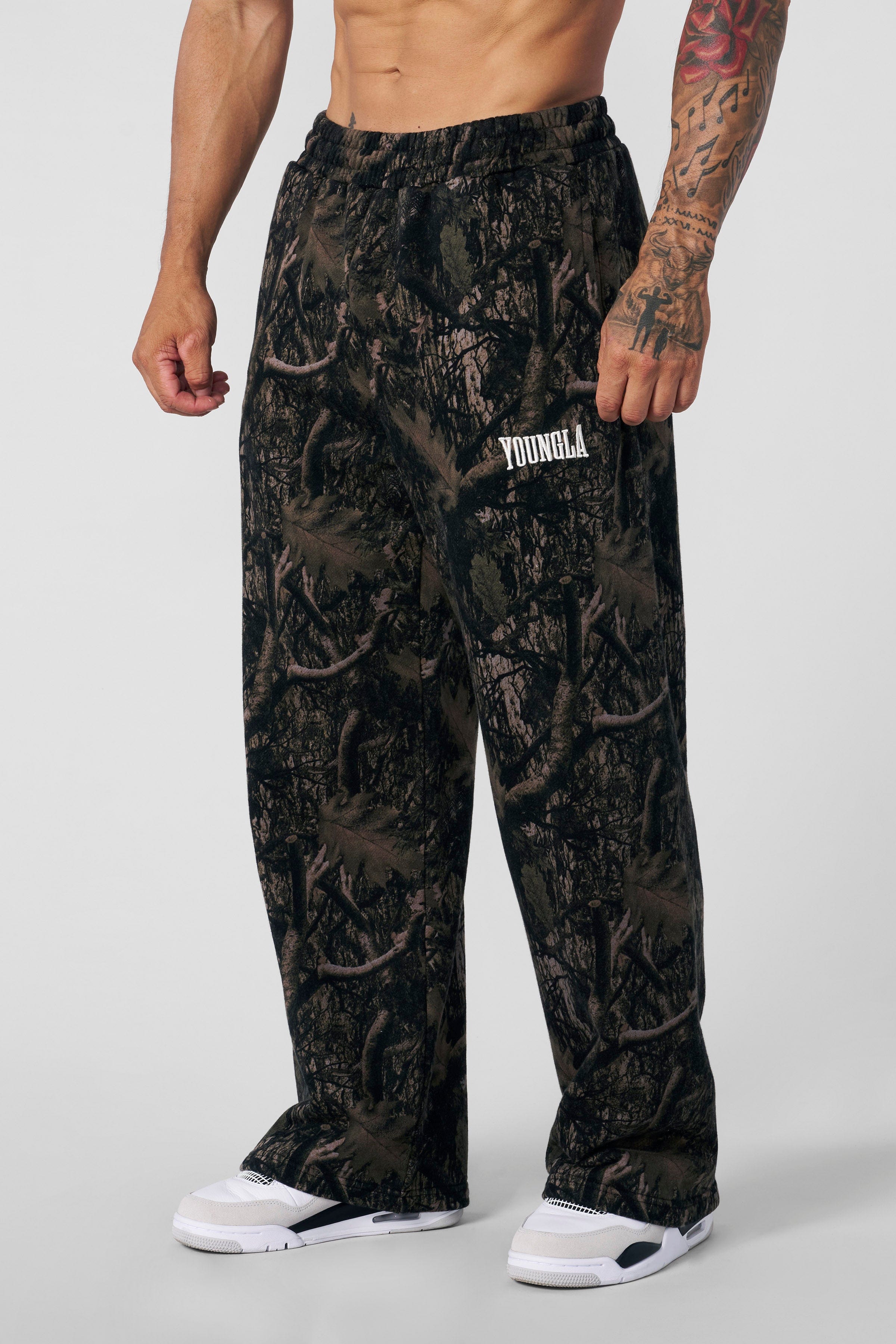 Model wearing YOUNGLA baggy camo sweatpants in a casual setting.