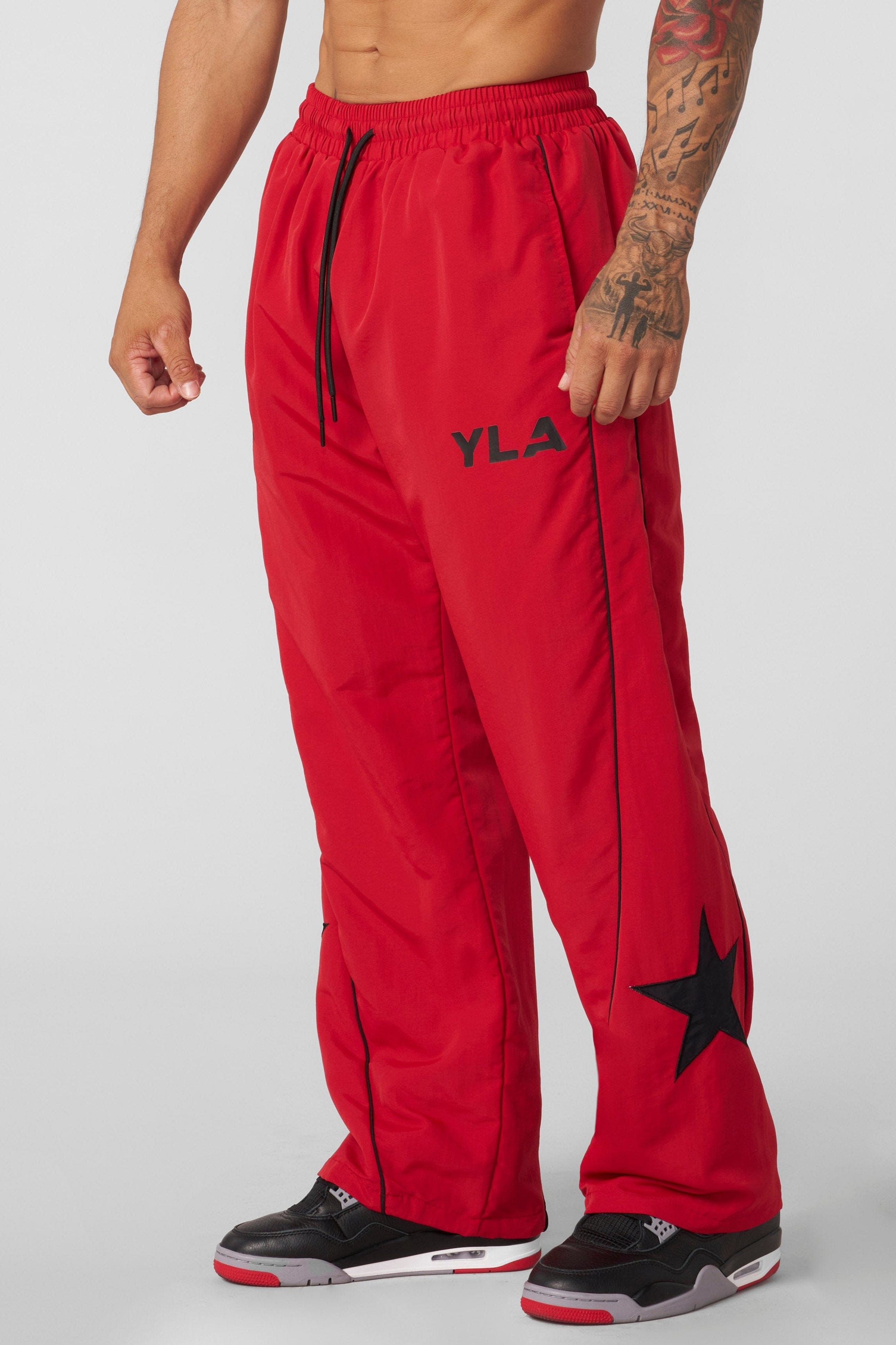 Front view of YoungLA x UFC tracksuit pants showcasing side piping and star patch