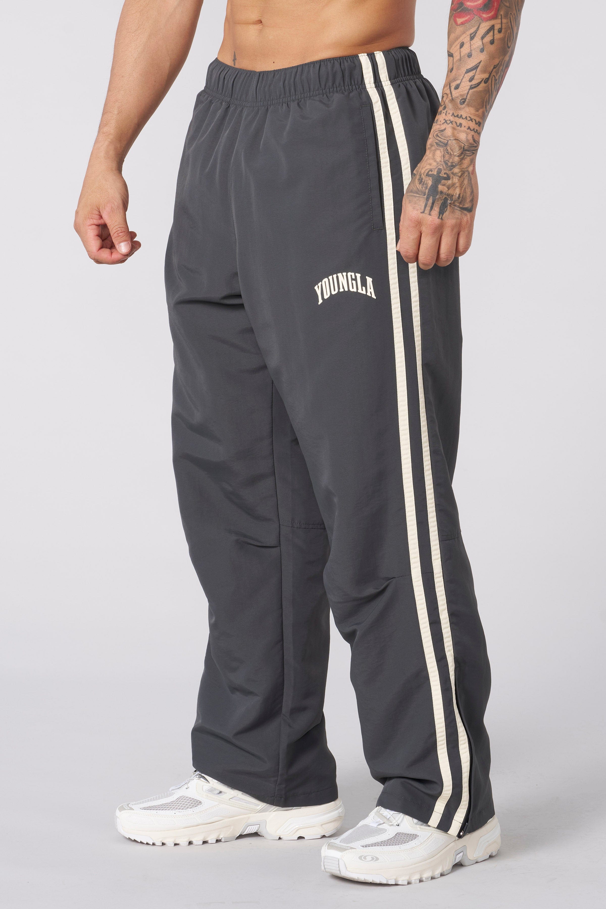 Front view of vintage-inspired track pants showcasing loose fit and side strips.