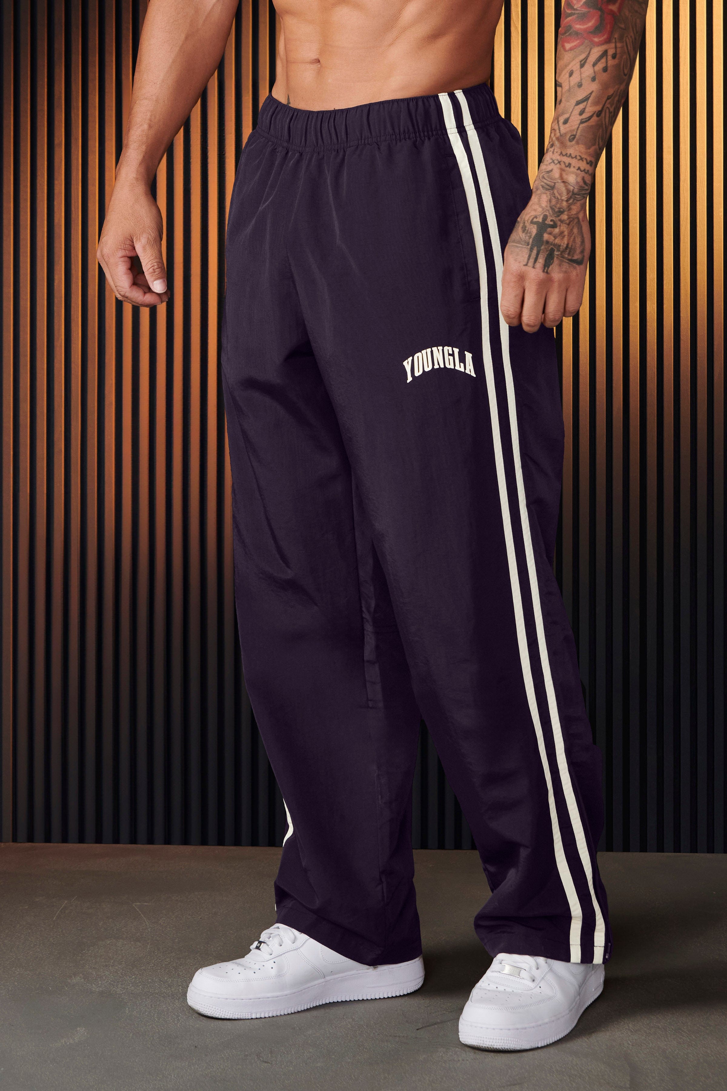 Front view of vintage-inspired track pants showcasing loose fit and side strips.