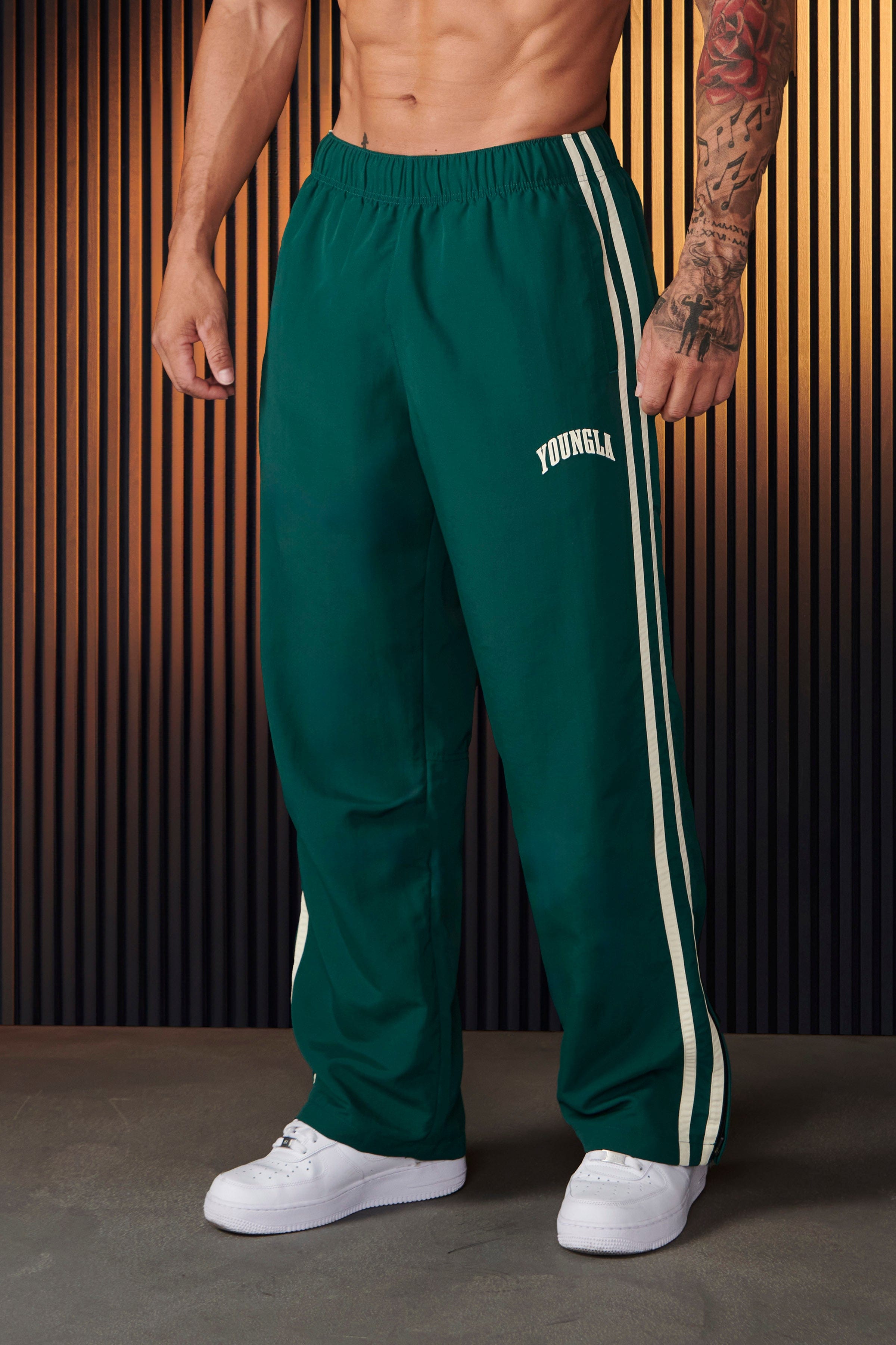 Front view of vintage-inspired track pants showcasing loose fit and side strips.