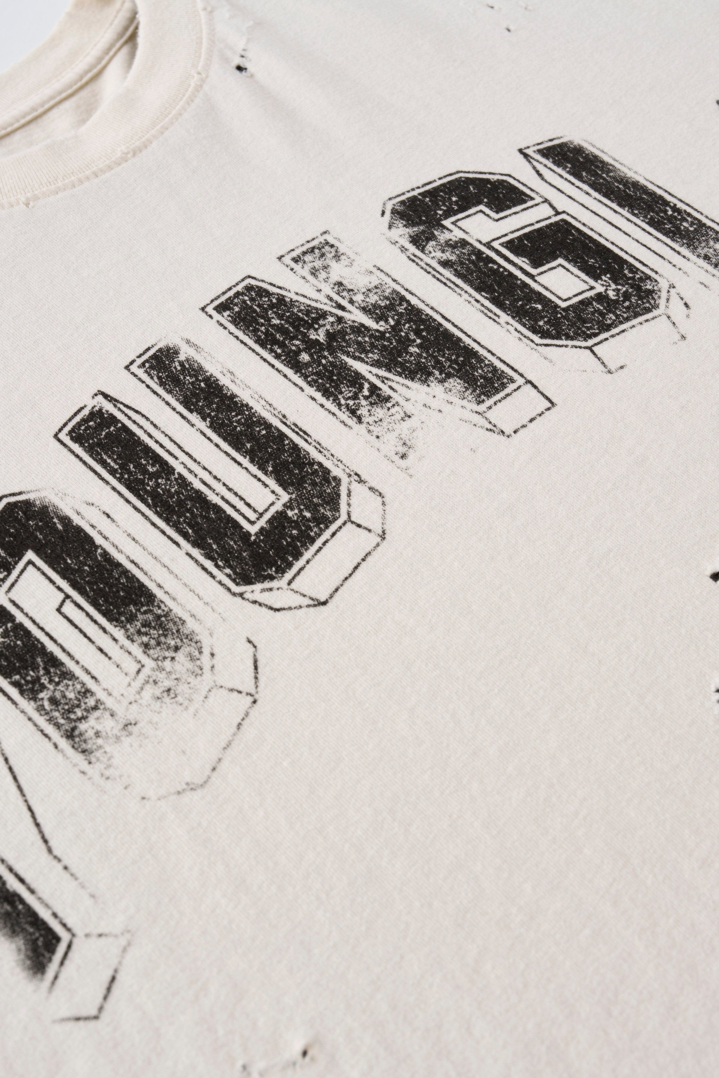 Close-up of vintage t shirt’s distressed cuts and arched logo