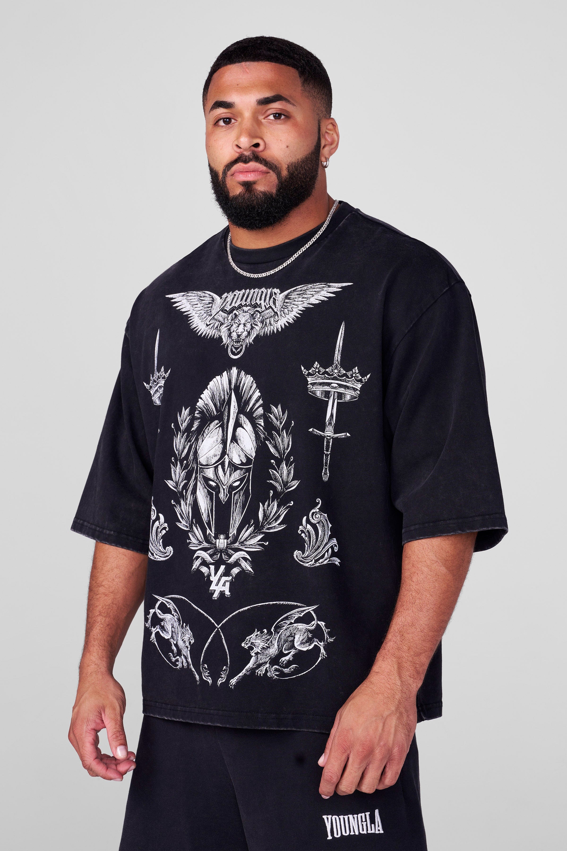 Front view of streetwear tee with royal battle graphics, worn in urban setting.
