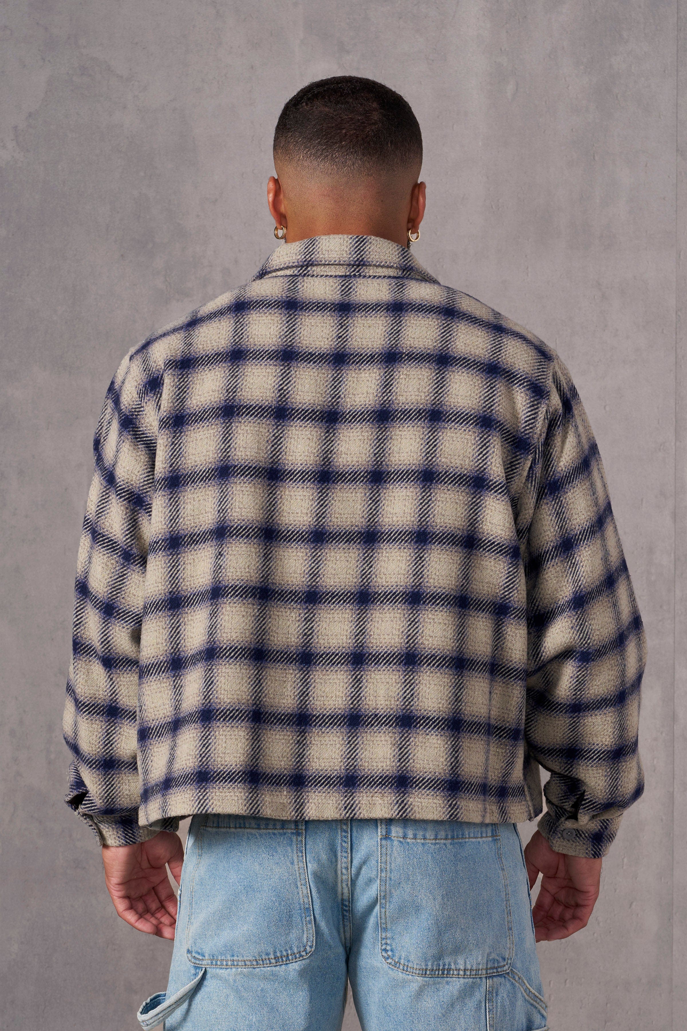 Model wearing the flannel shirt jacket outdoors, hands in pockets.