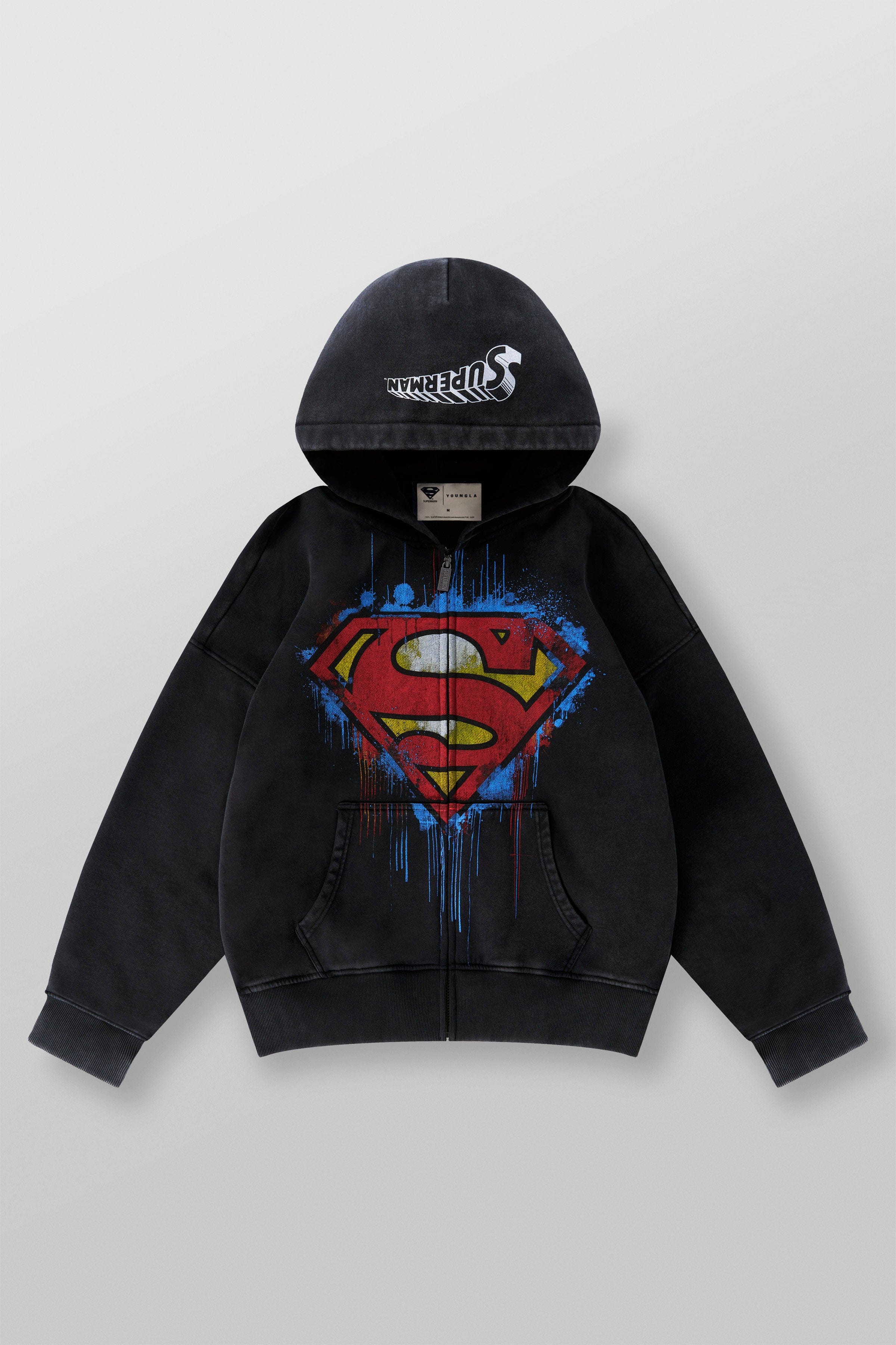 Front view of the Superman camouflage zip-up sweatshirt worn by a model in an urban backdrop.
