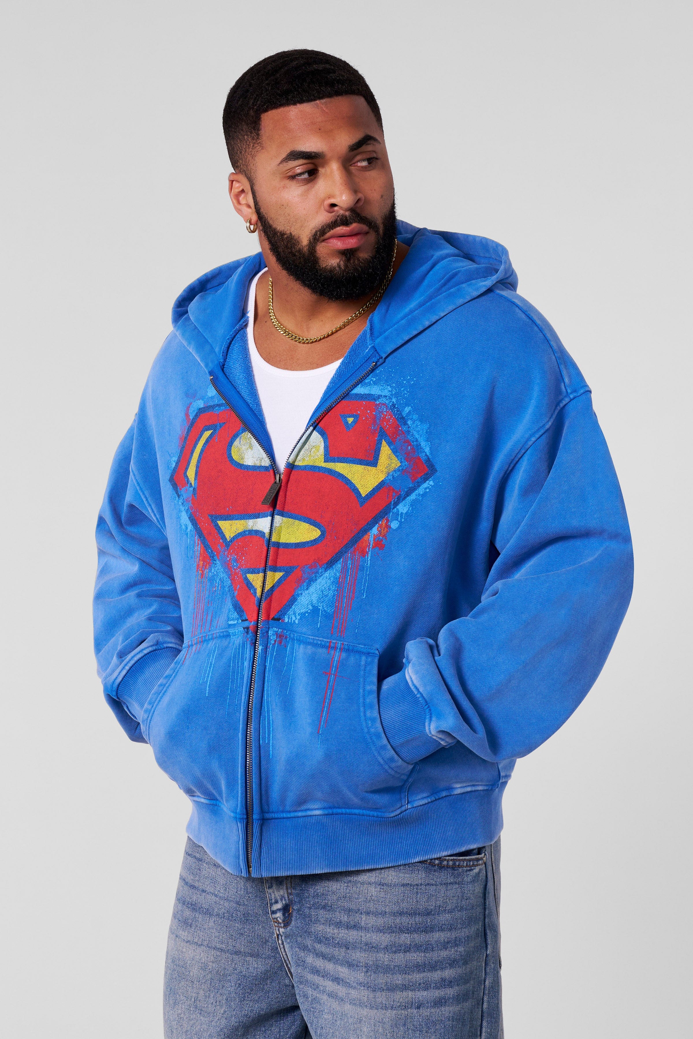 Side view of the model wearing the Superman zip-up sweatshirt, showcasing its relaxed fit.