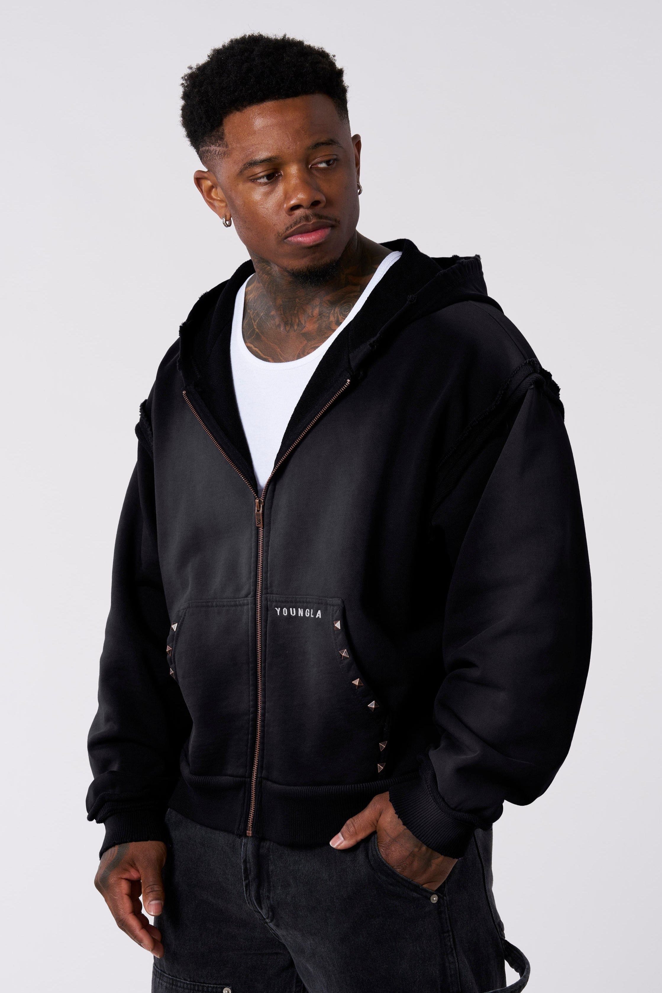 Close-up of raw seams and studs on the pocket of the oversized hoodie
