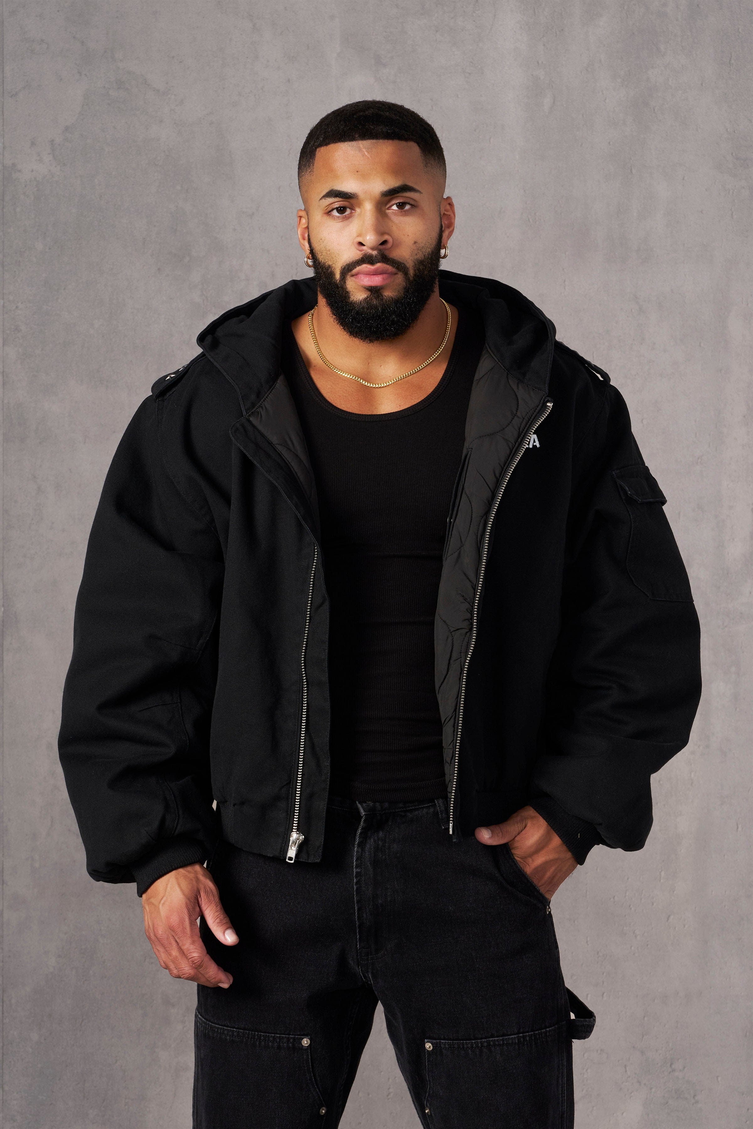 Side profile of a model in a ladies black aviator jacket with urban backdrop