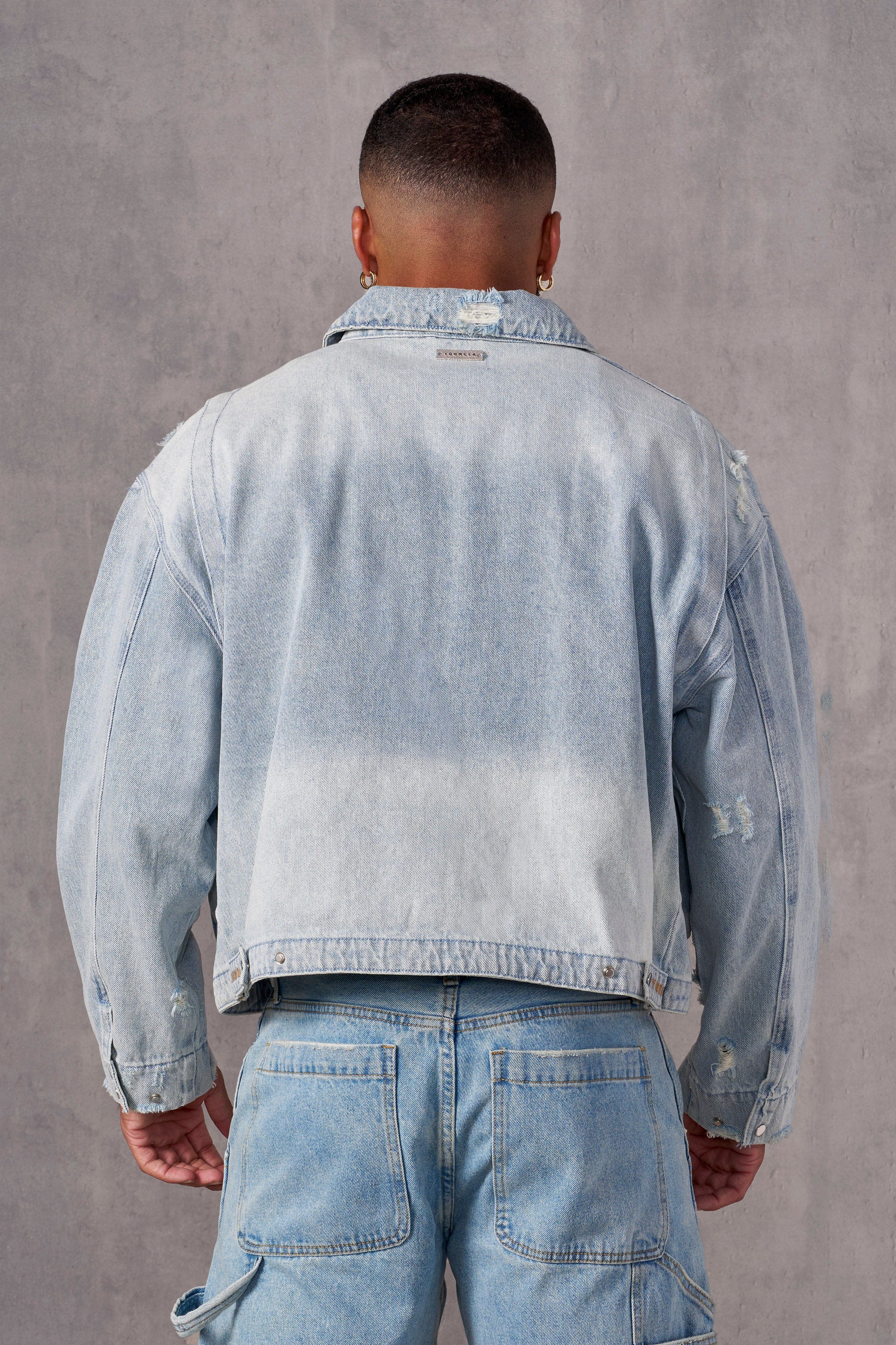 Back angle of jean jacket showing distressed cut and branding details