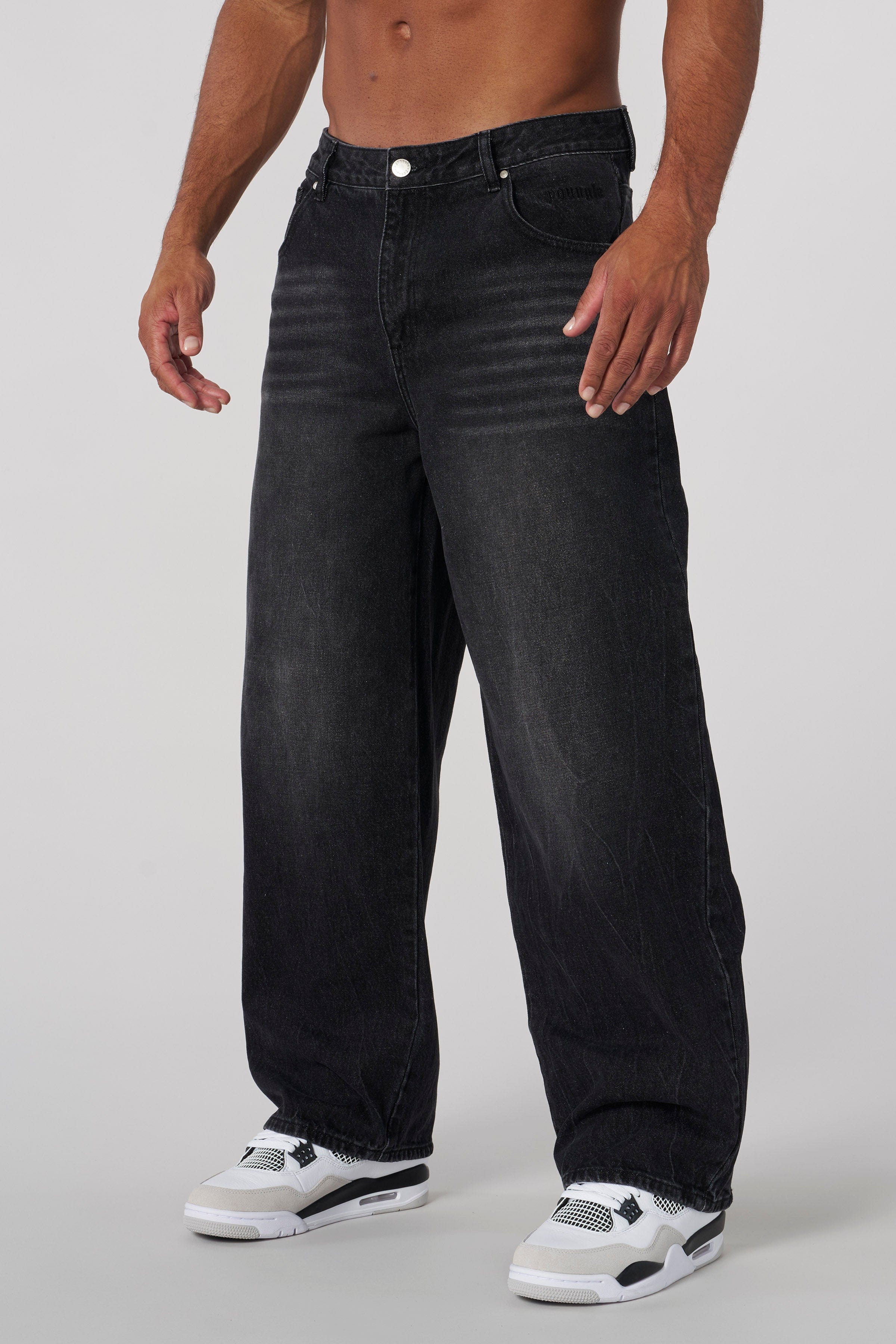 Front view of low rise baggy jeans styled with high-top sneakers on city sidewalk