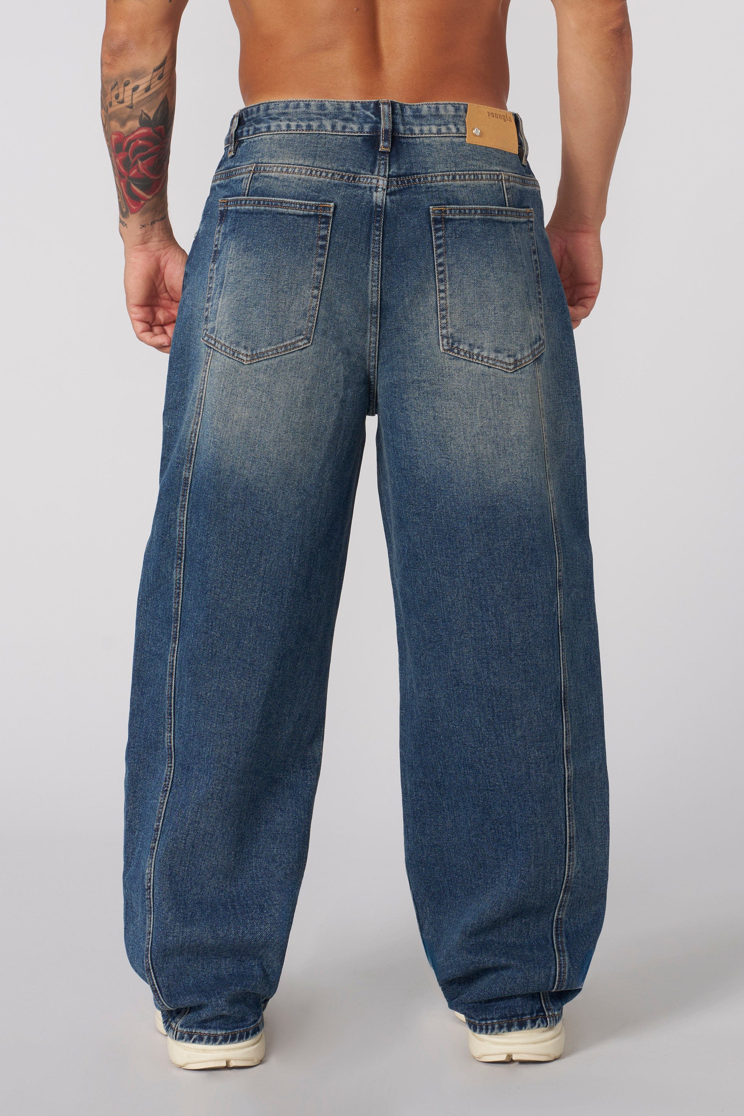 Side angle of baggy black jeans showing relaxed fit and washed texture