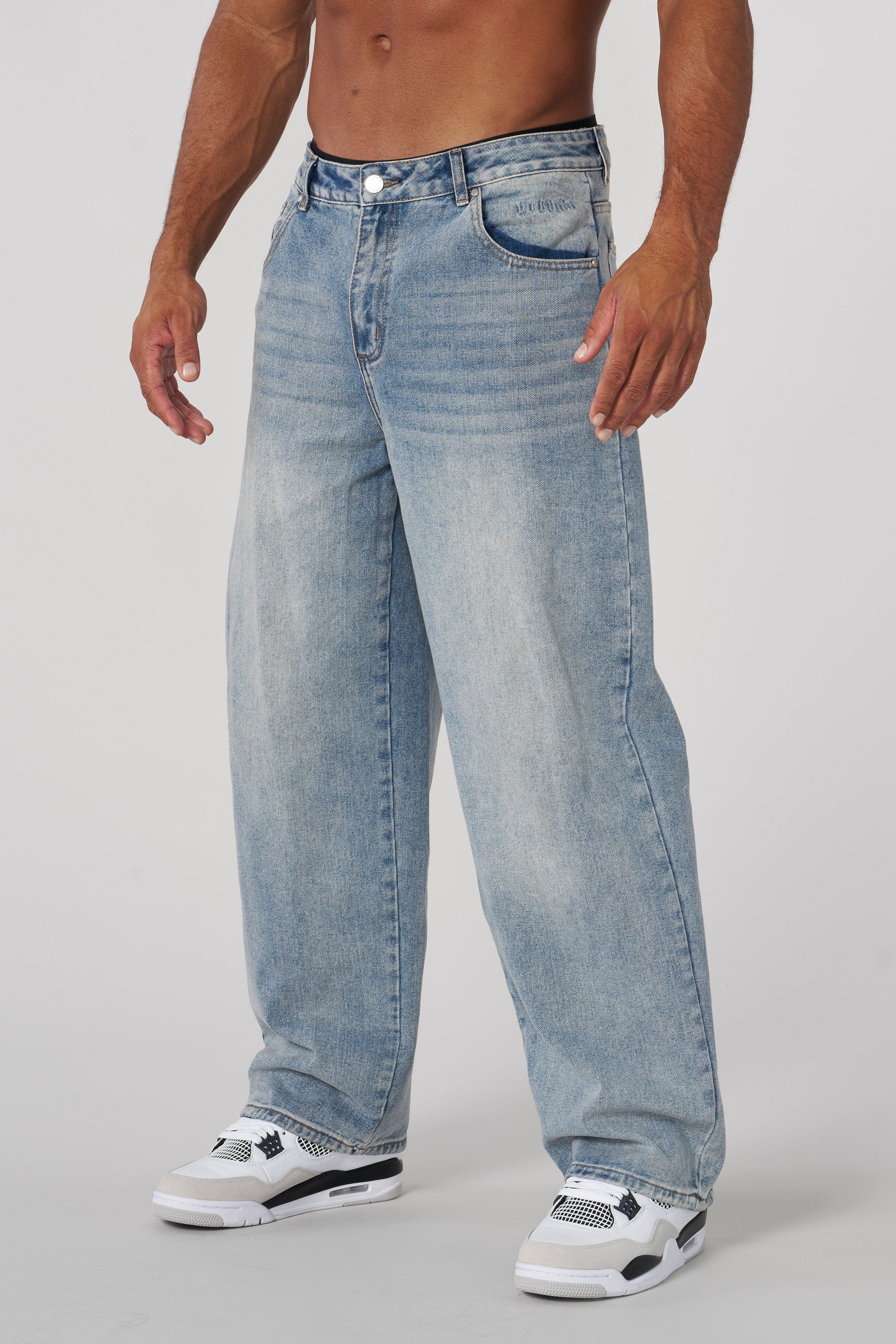 Front view of low rise baggy jeans styled with high-top sneakers on city sidewalk