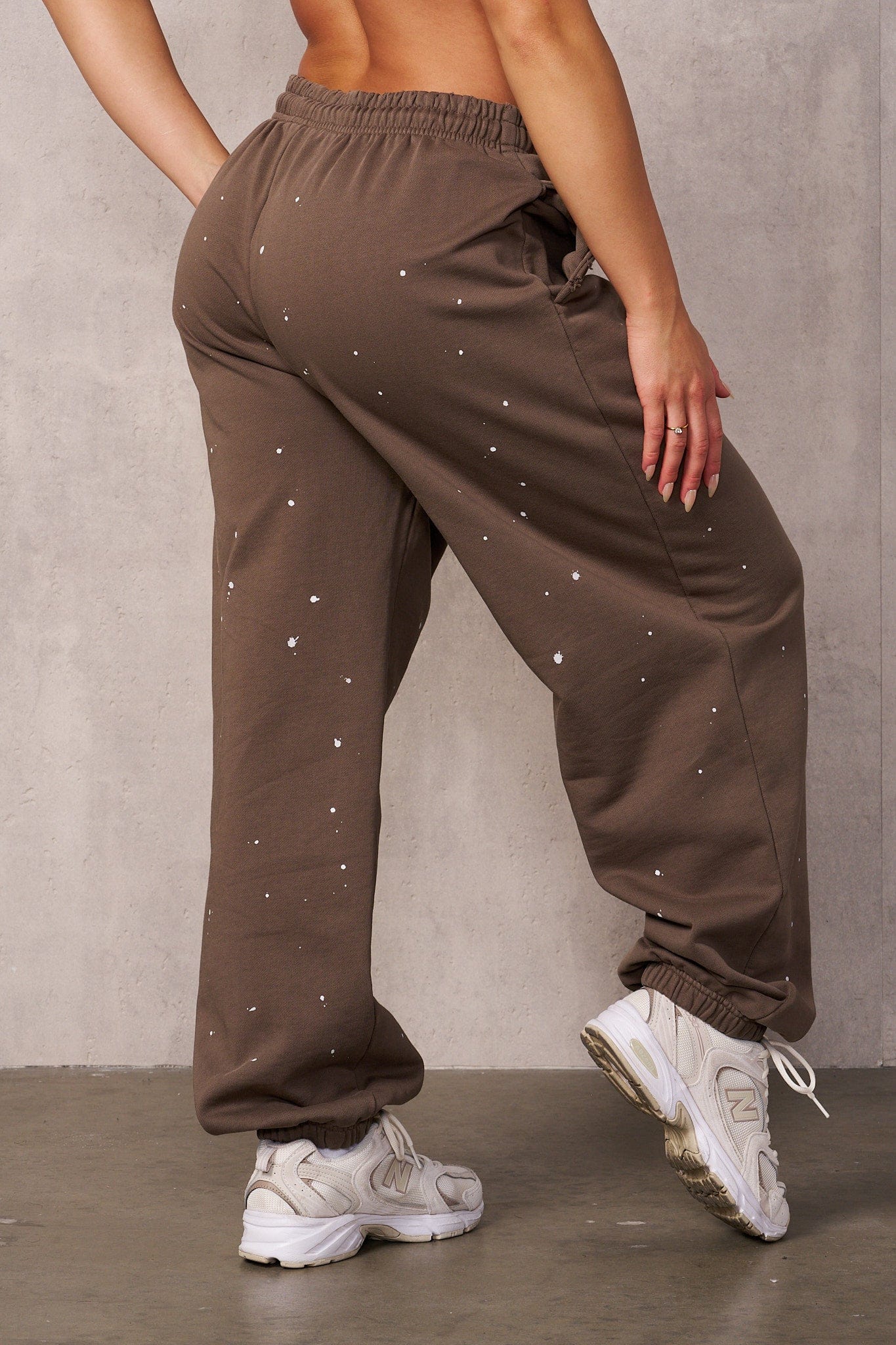 Side profile of the model wearing black oversized sweat pants with urban backdrop.