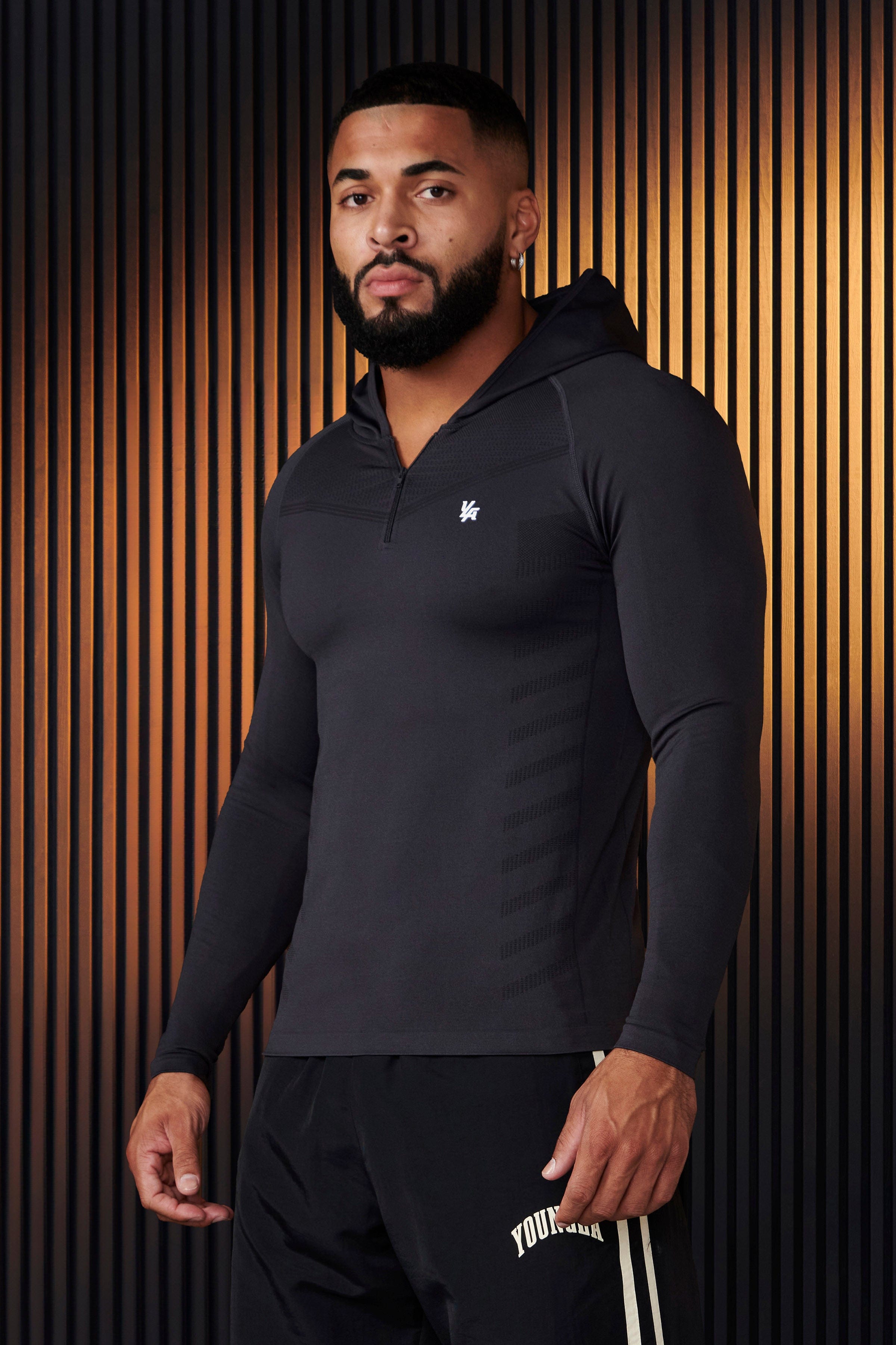 Side angle of compression hoodie emphasizing fit and fabric texture in gym lighting.