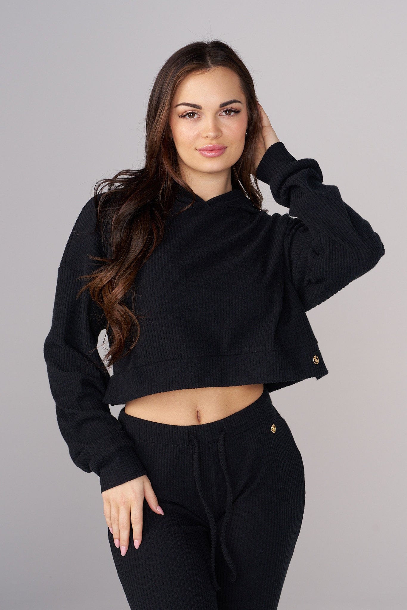 Woman wearing a cropped black hoodie with hands in pockets, urban backdrop