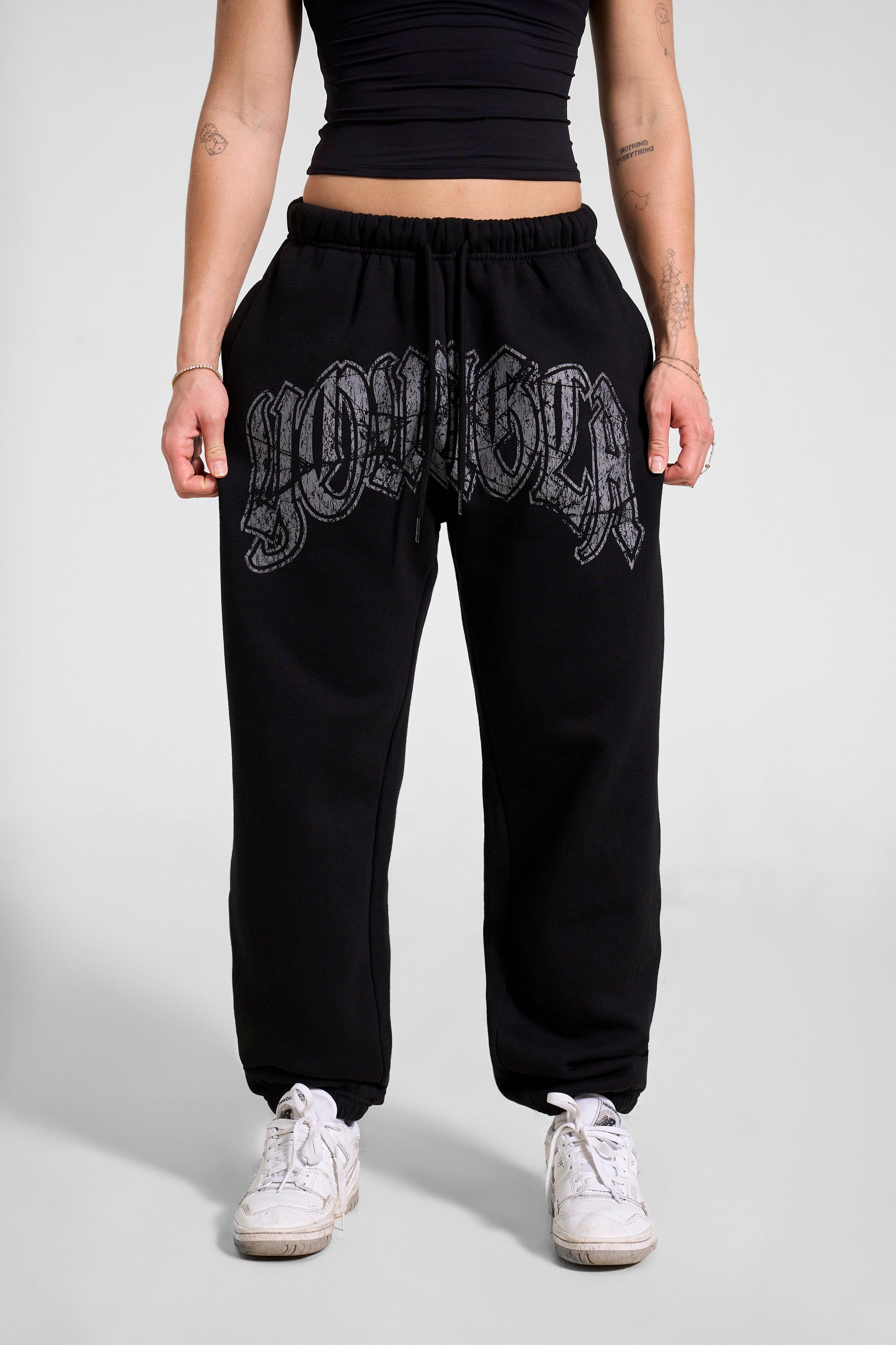 Front view of stylish black joggers for women with a cracked print logo.