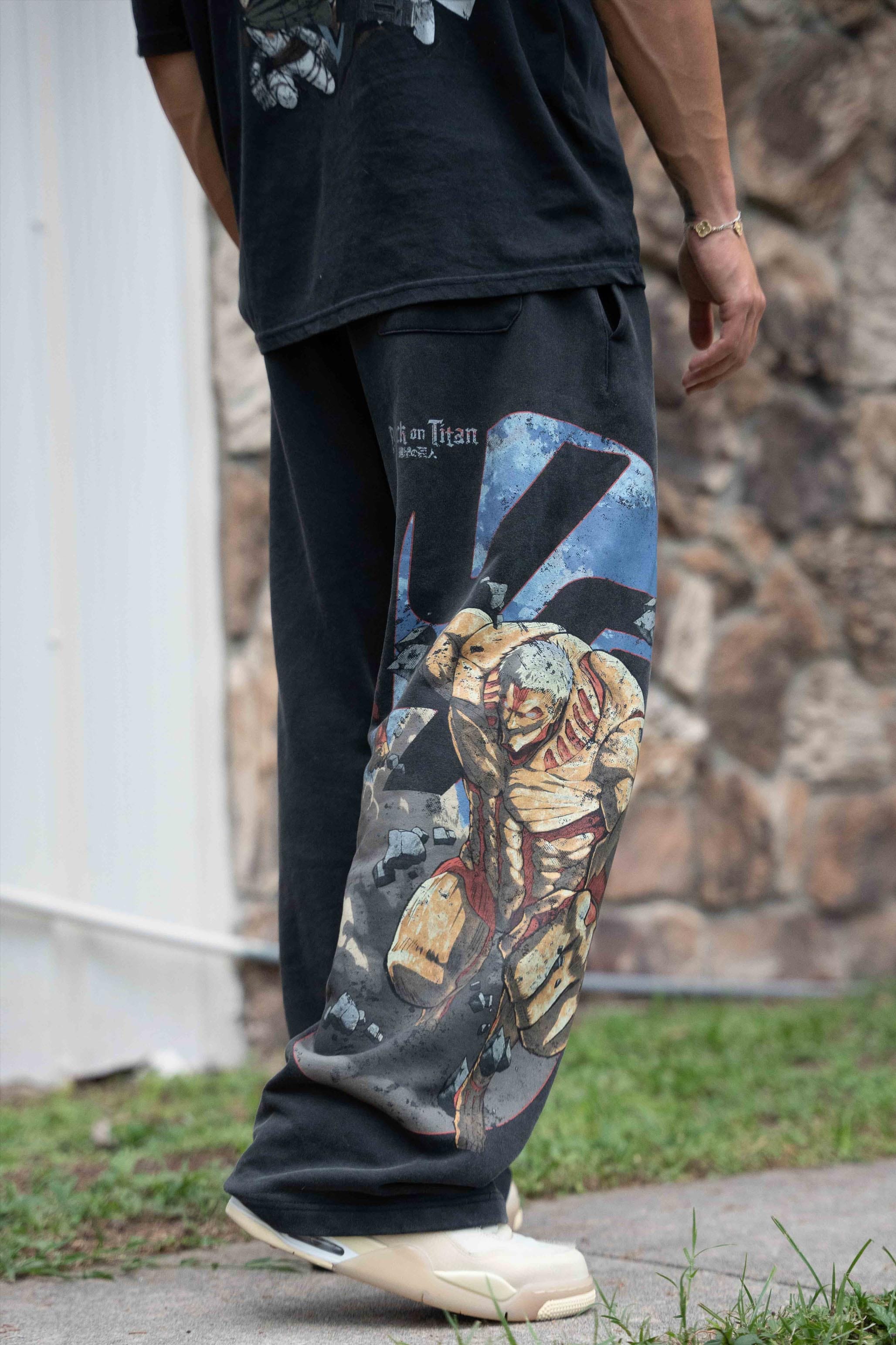 Model wearing black baggy joggers in an urban setting, embodying anime streetwear style.