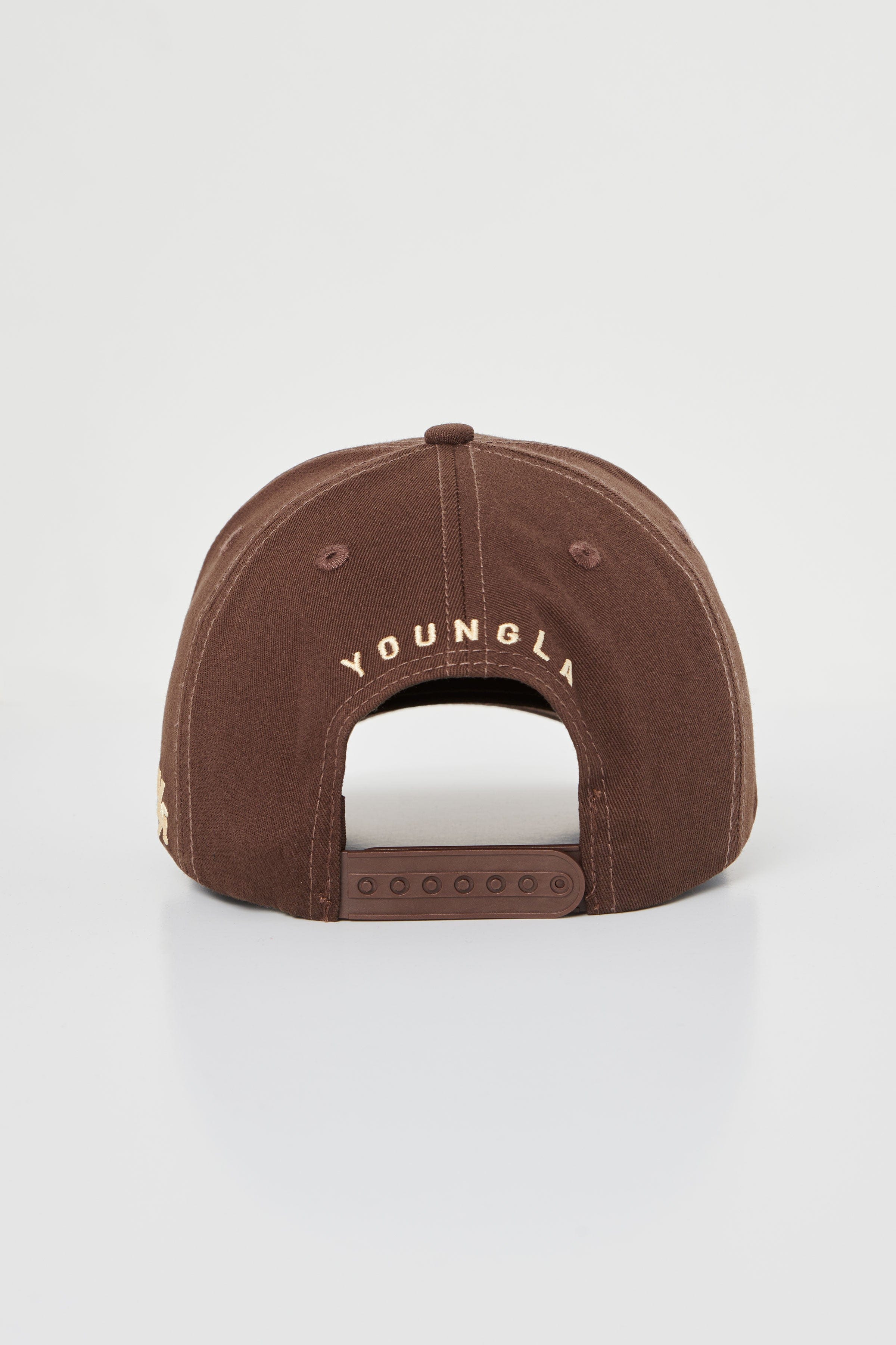 Side angle showing custom snapback hat fit and embroidery across twill fabric in earthy tones.