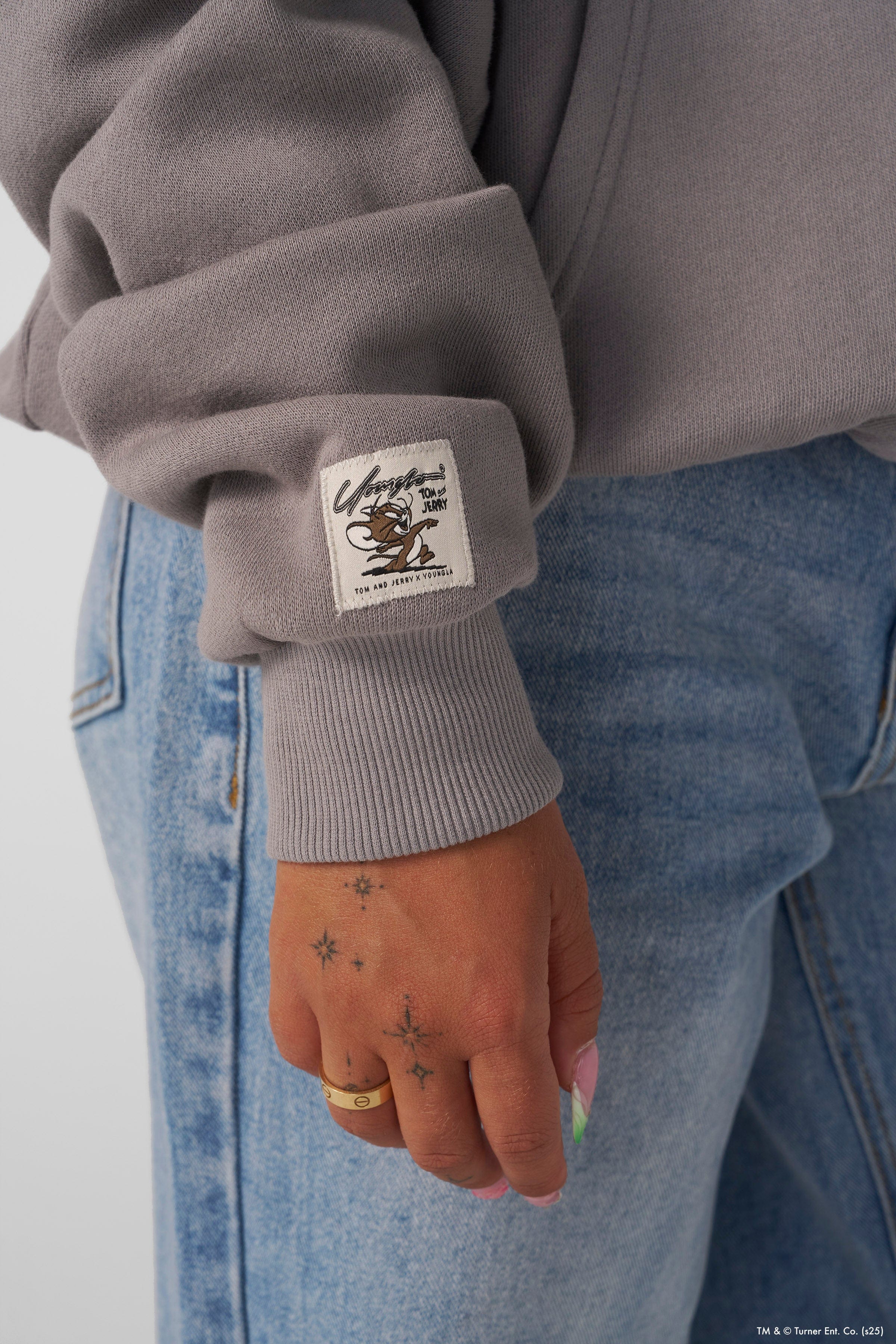 Close-up of a black graphic hoodie featuring Tom & Jerry cartoon print, casual style