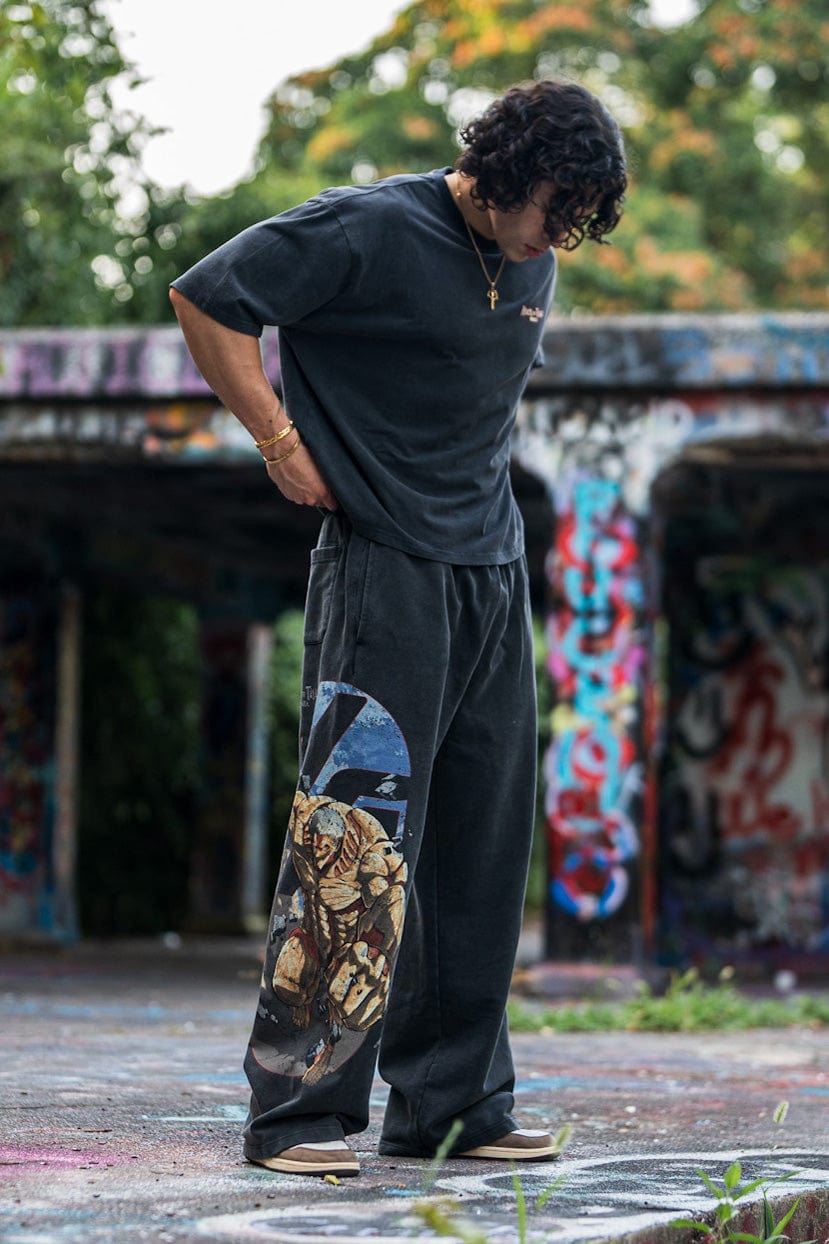 Model wearing black baggy joggers in an urban setting, embodying anime streetwear style.