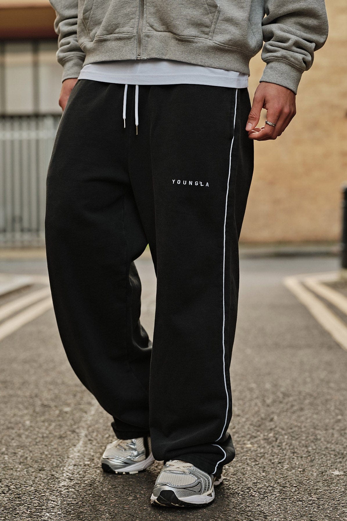 Model wearing baggy gray sweatpants in a relaxed outdoor setting