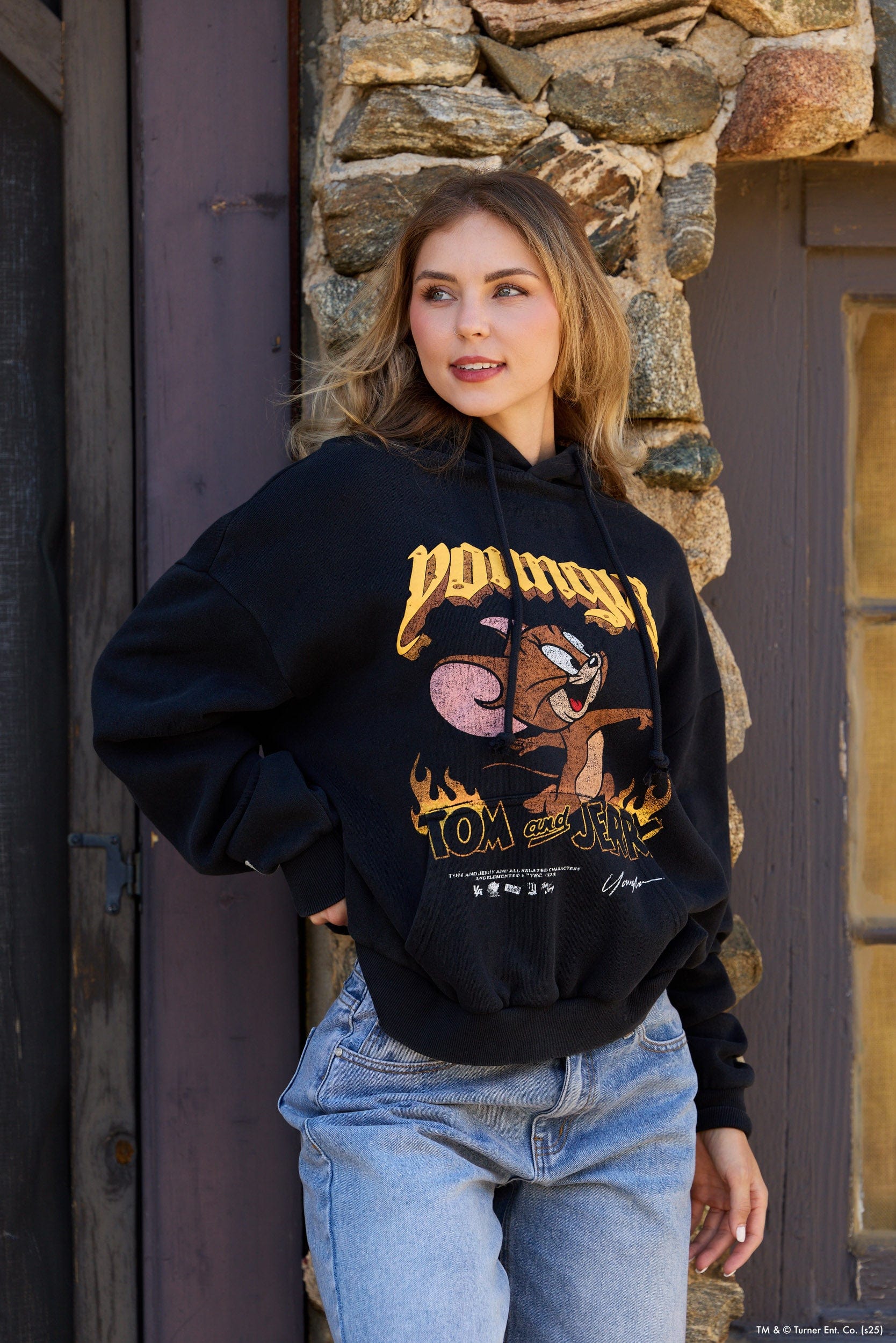 Close-up of a black graphic hoodie featuring Tom & Jerry cartoon print, casual style