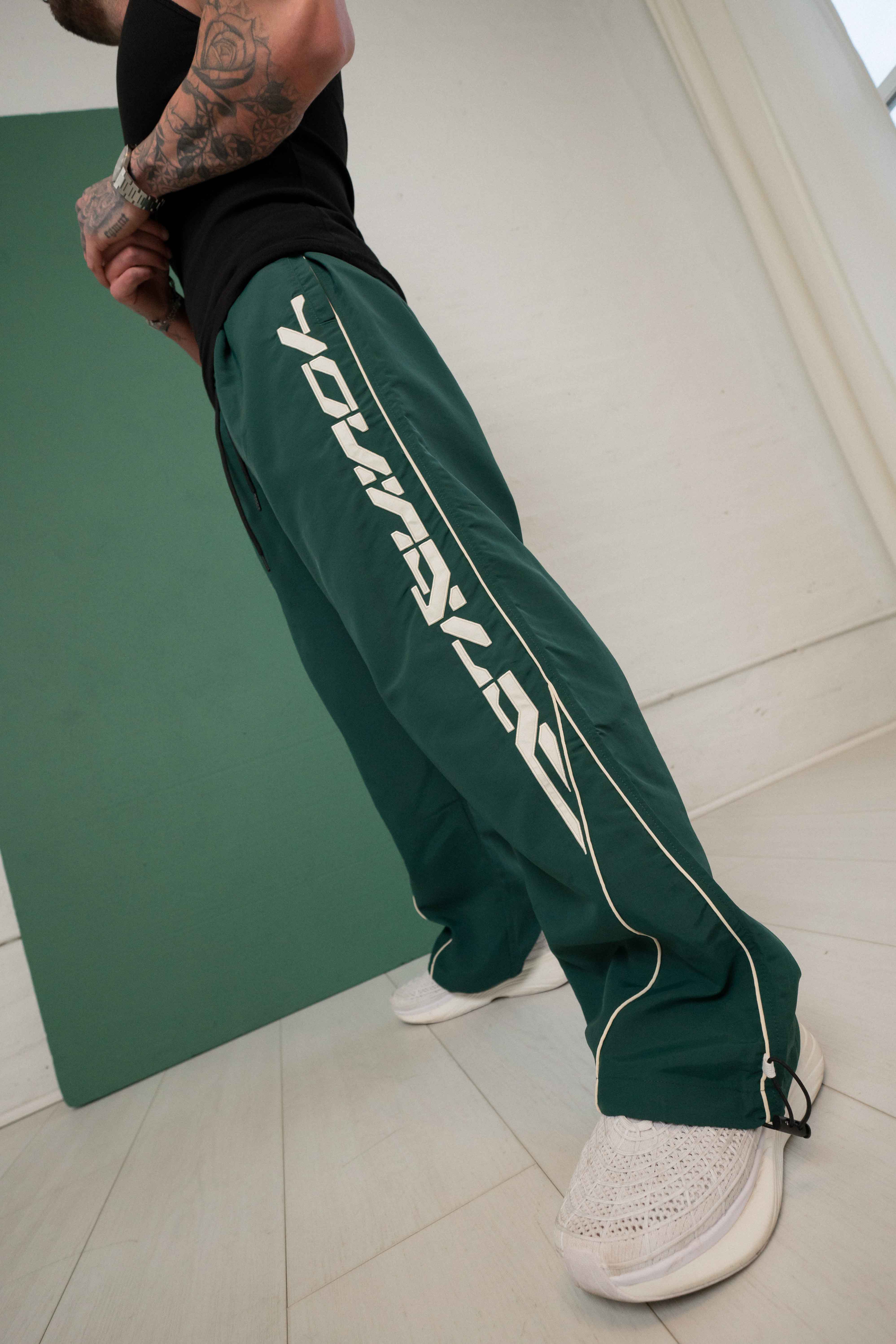 Side view of track pants highlighting the patch logo and lightweight fabric.