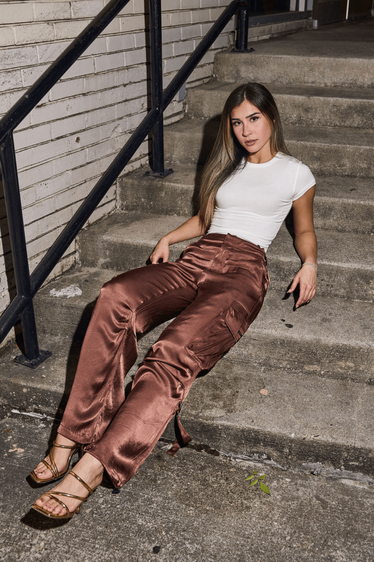 Model wearing black satin cargo pants with a casual white tee