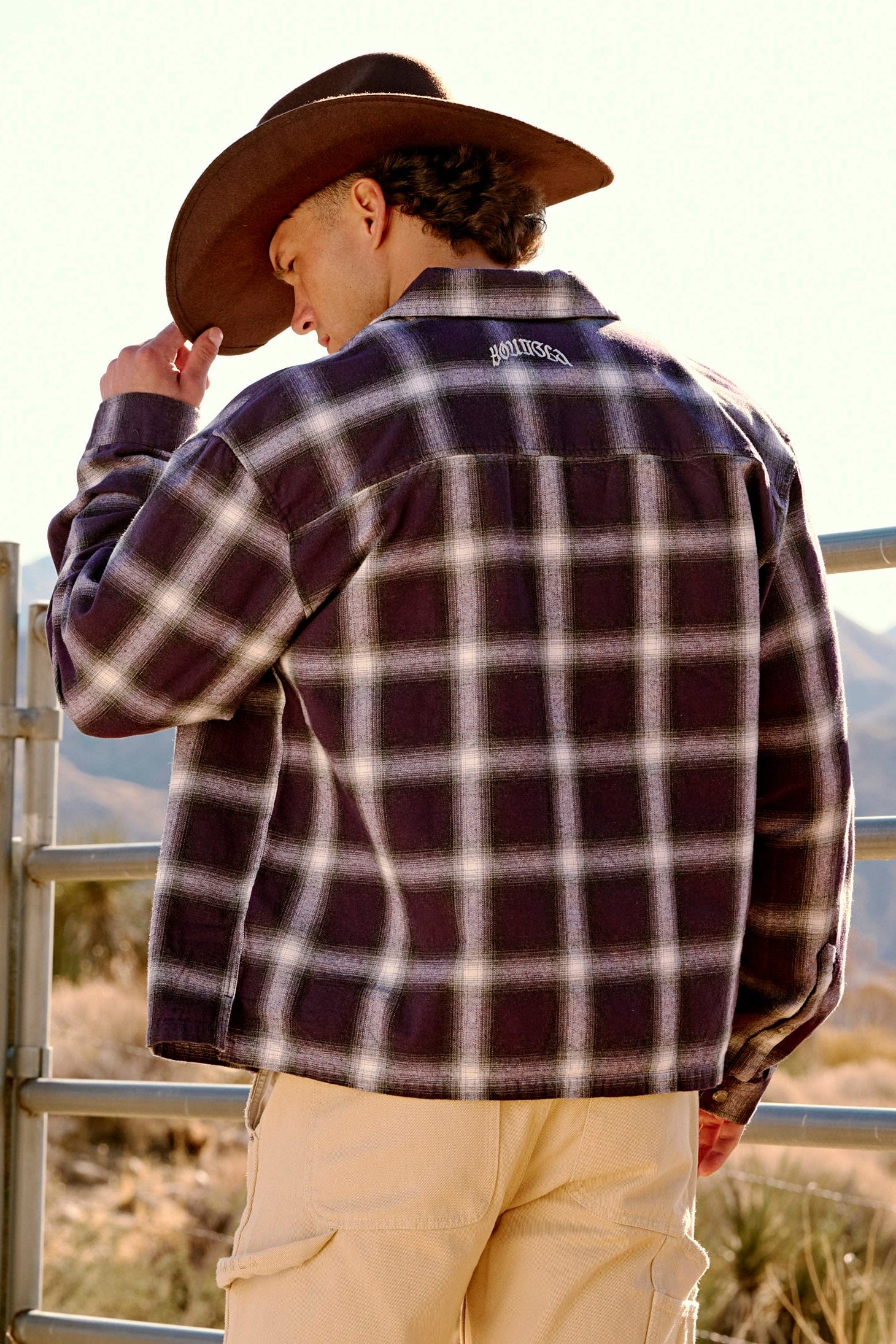 Full-body image of a man wearing layered flannels during an outdoor city stroll.