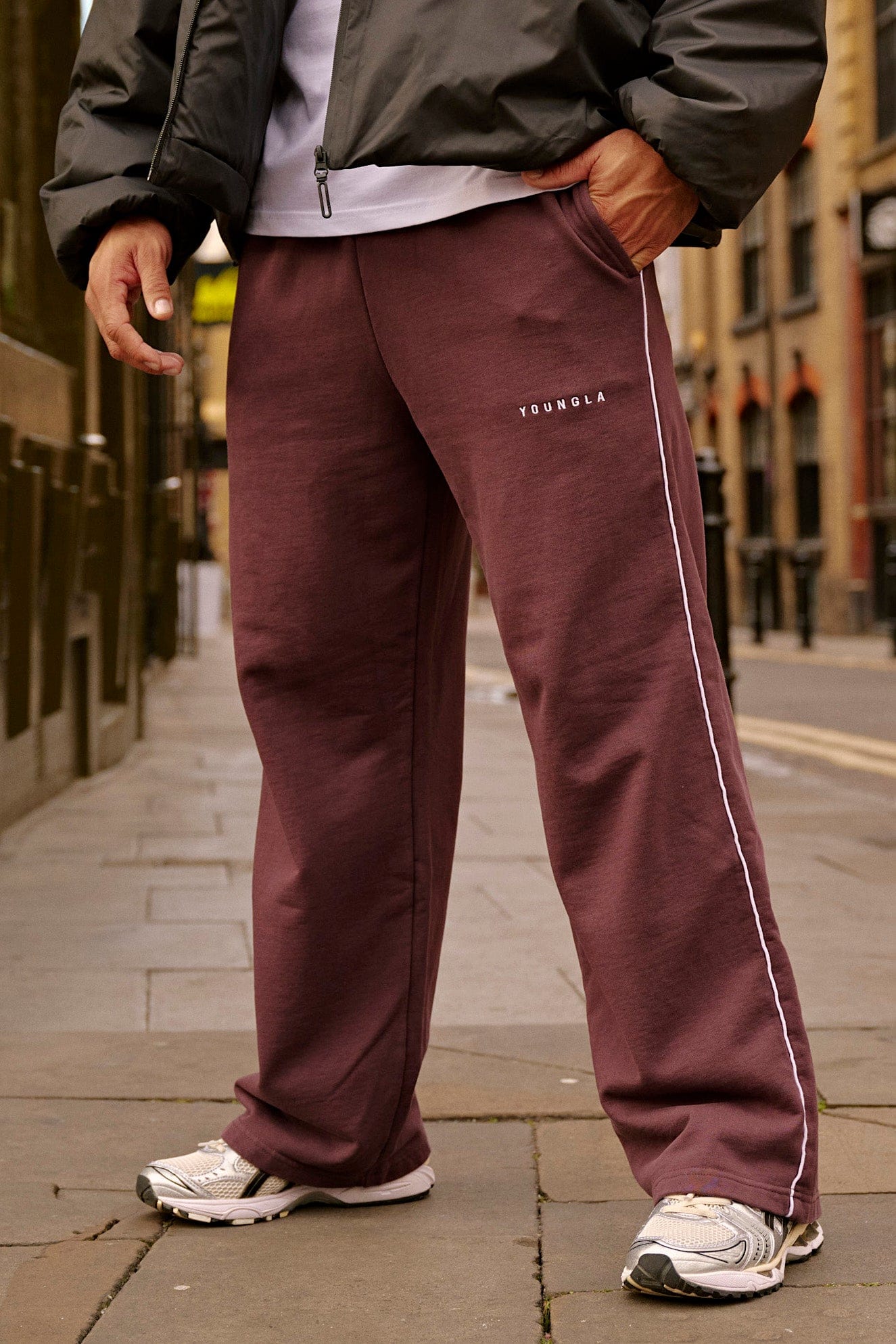 Model wearing baggy gray sweatpants in a relaxed outdoor setting
