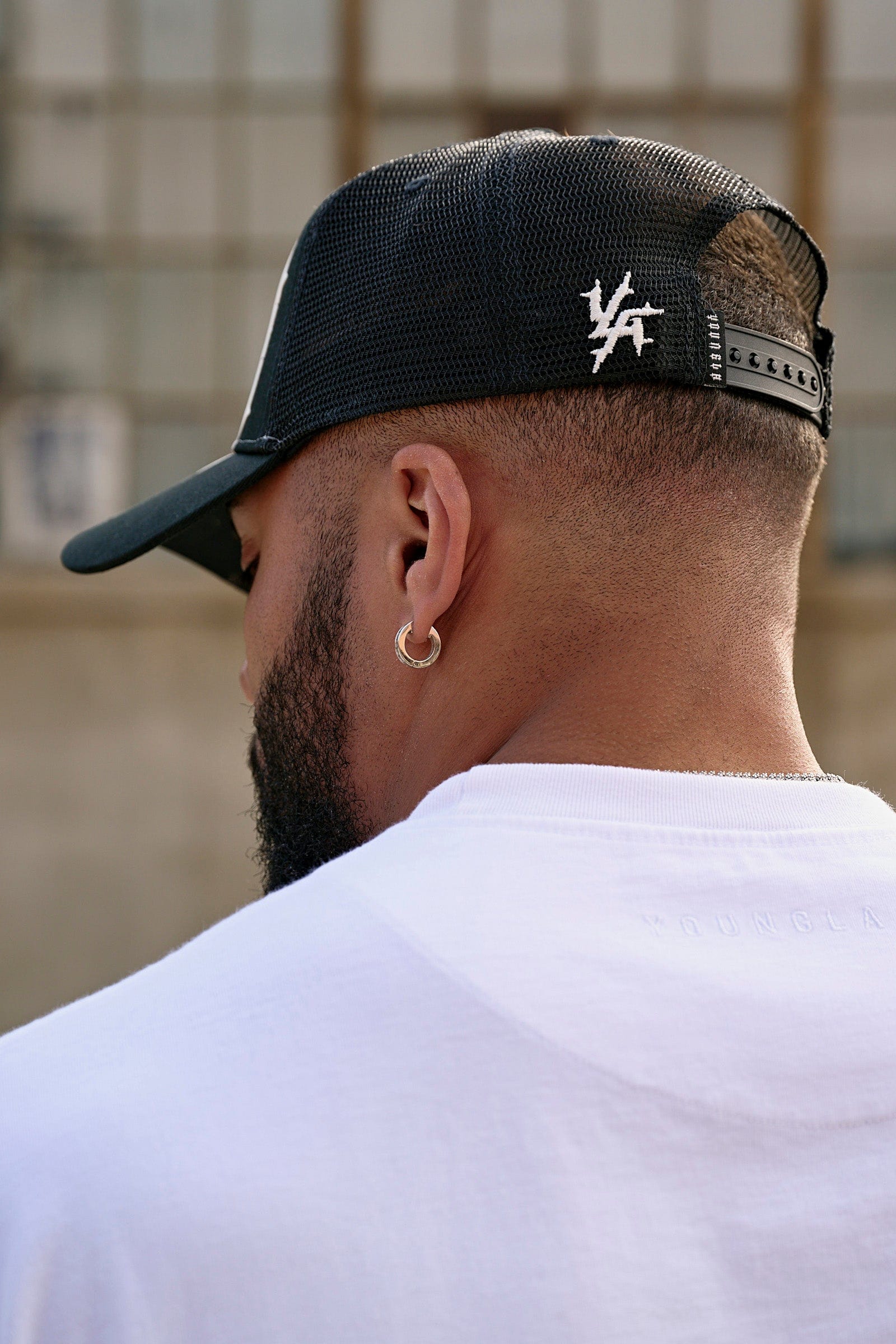 Side view of logo hats styled with denim jacket in urban setting