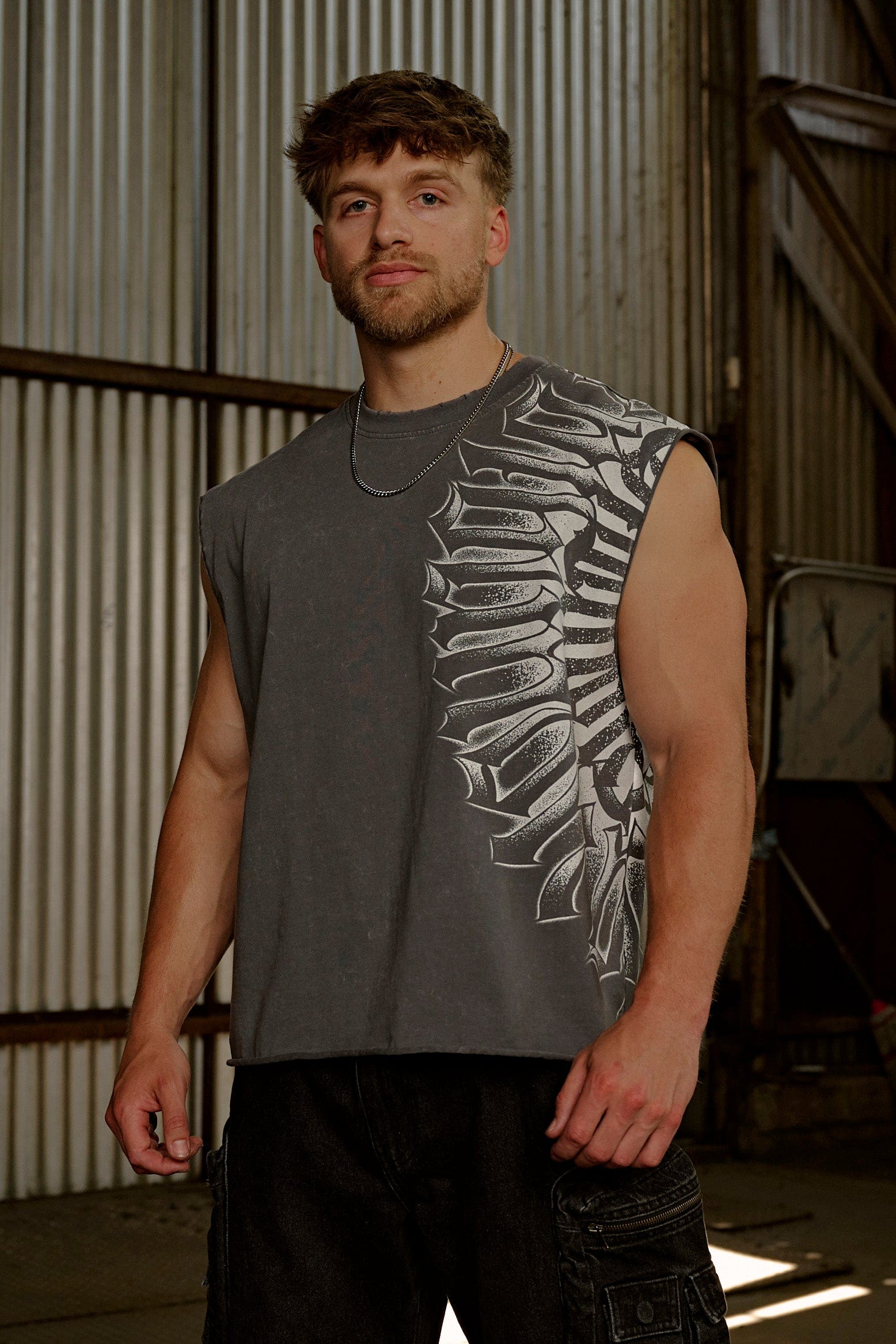 Front angle of muscle tank top worn by male model in urban setting.